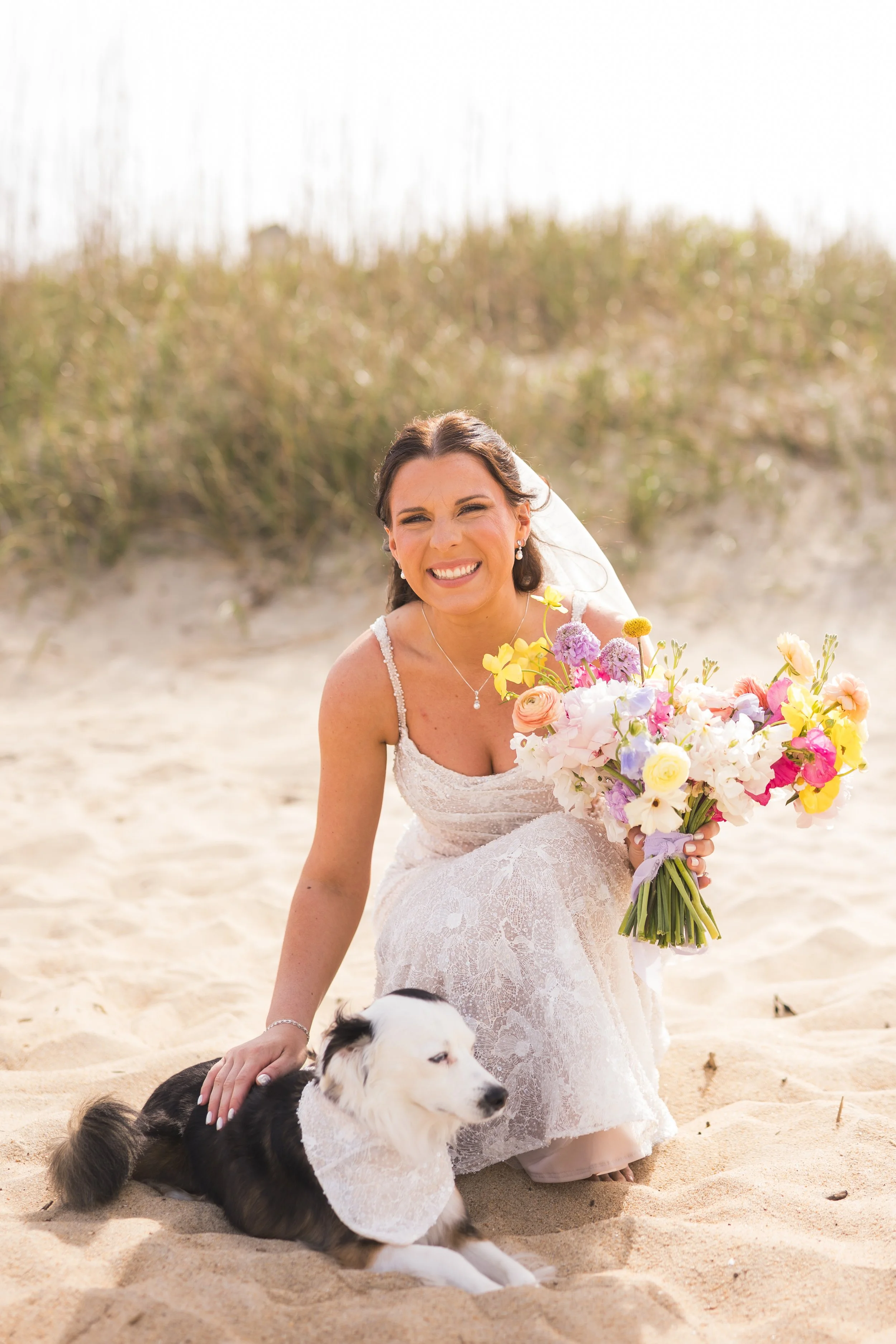 Bride with dog on Outer Banks beach holding whimsical bouquet for preservation by Beaux’s Botanicals
