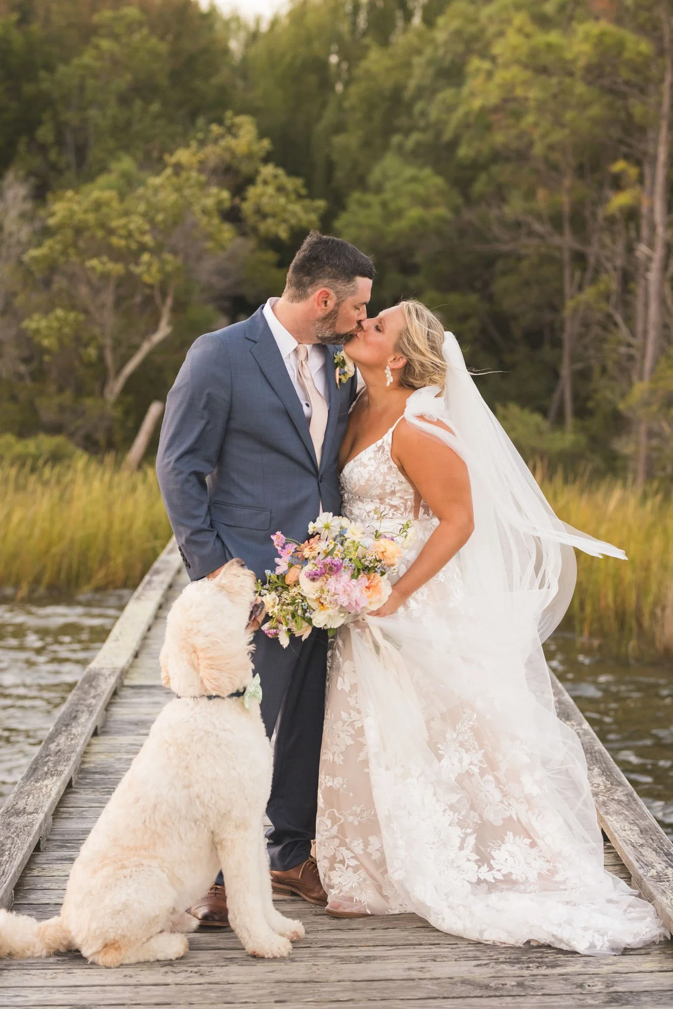Wedding couple with their dog on a pier holding a bouquet later preserved by Beaux’s Botanical Preservation in Outer Banks NC
