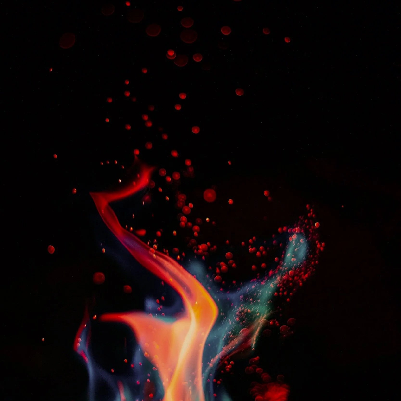 Colorful flames with red and orange hues against a black background, creating abstract shapes and patterns.