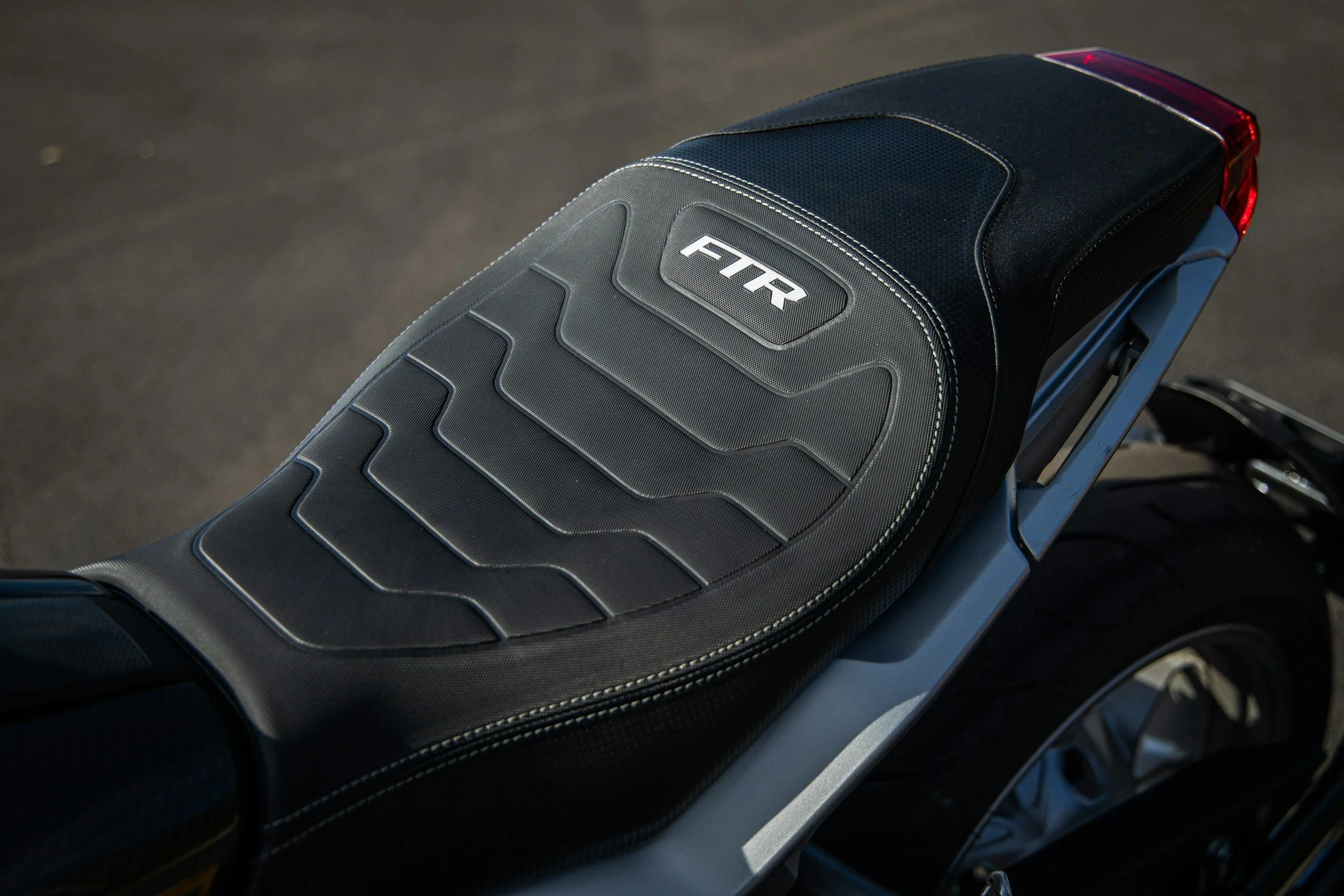 Close-up of a motorcycle seat with black upholstery and the logo 'FTR' embroidered on it.