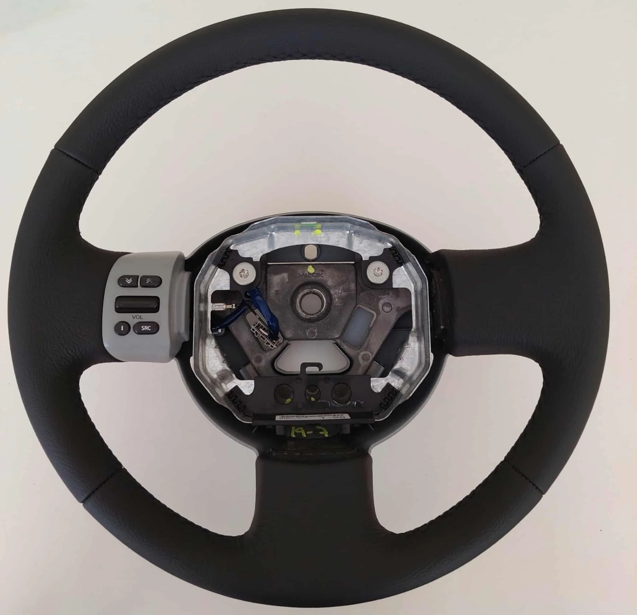 A car steering wheel with buttons and exposed internal components.