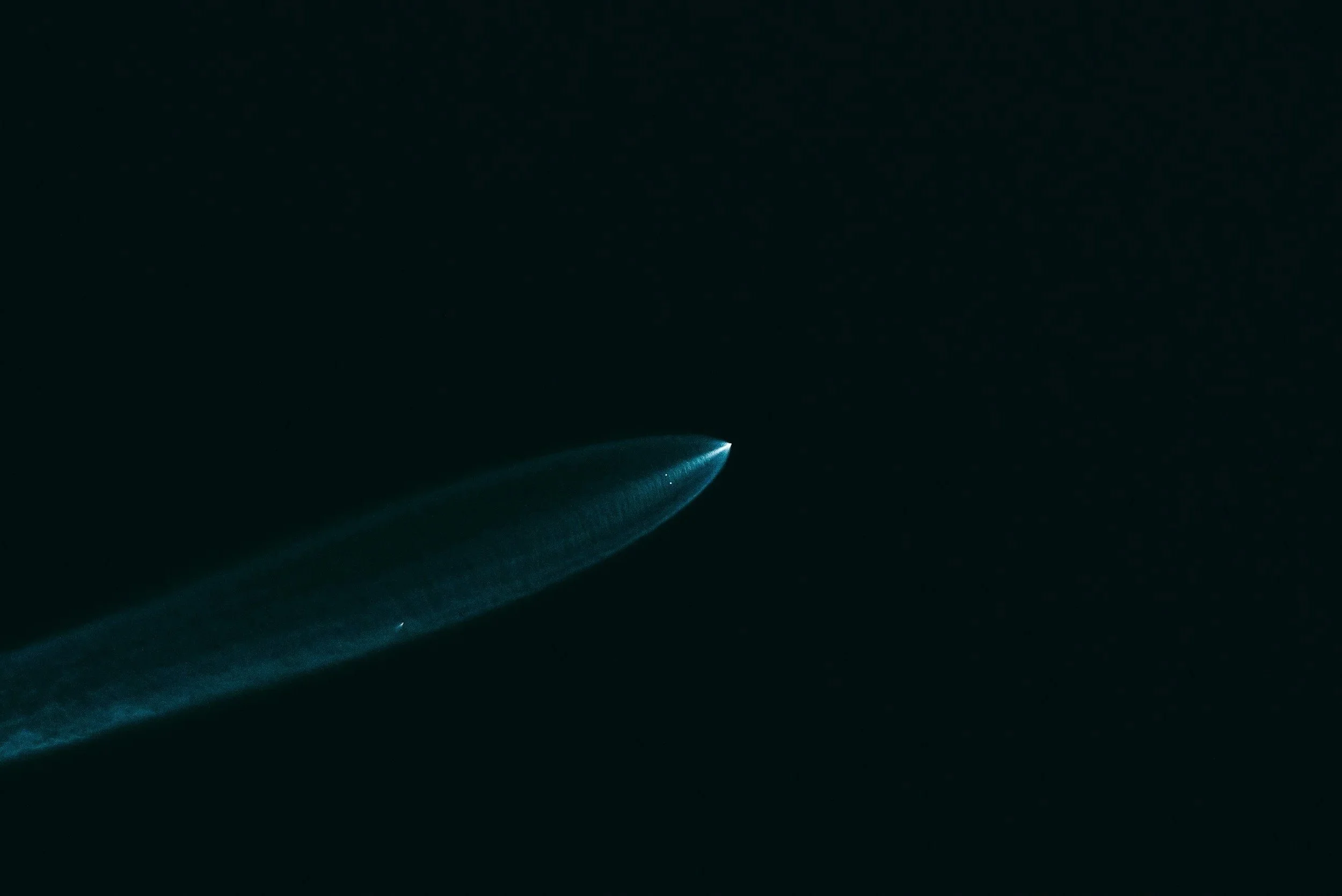 A bright object, possibly a comet or meteor, flashing across a dark night sky with a glowing tail.