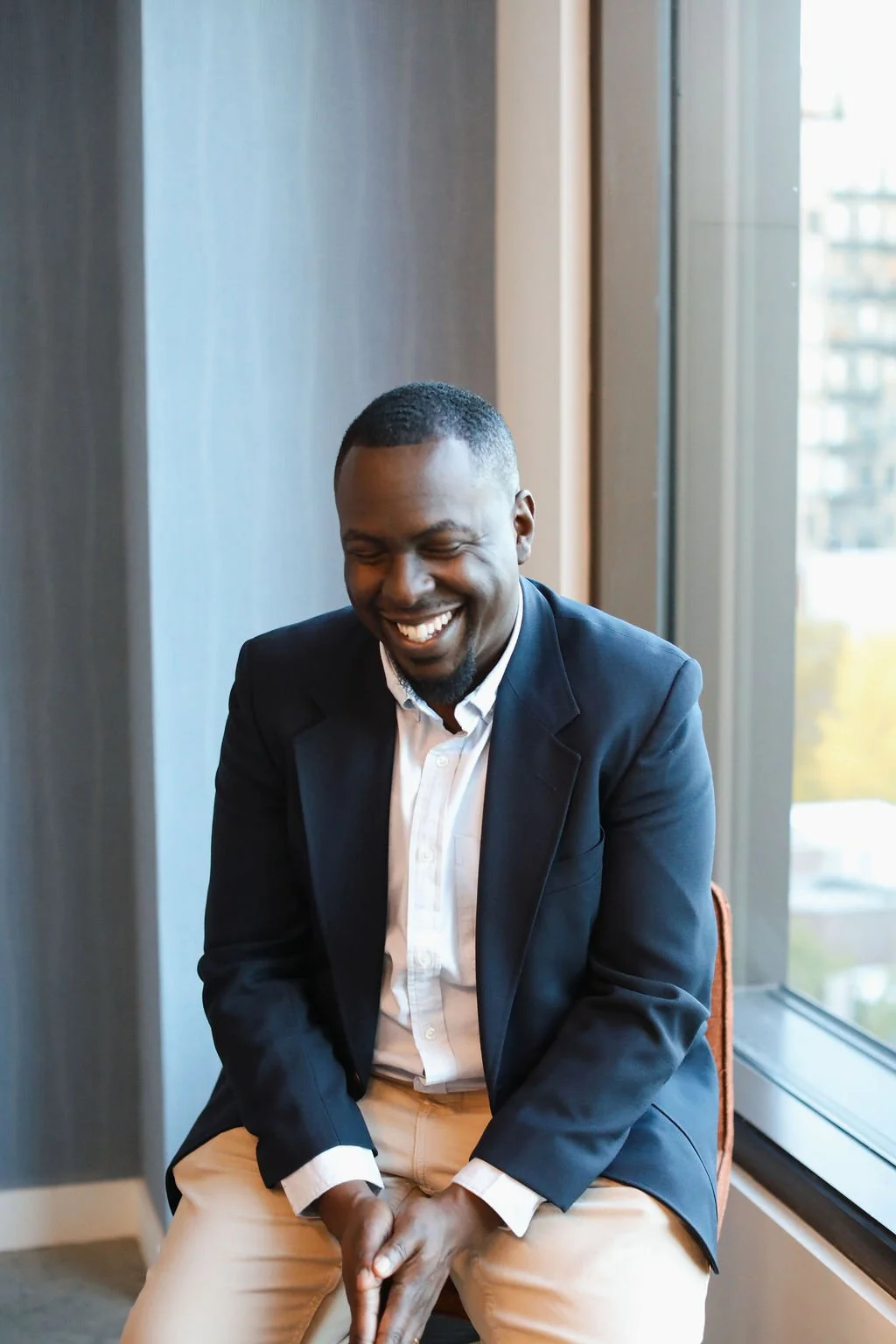 Brandon Dunkley, spiritual director and ministry consultant sitting on chair while looking down and smiling