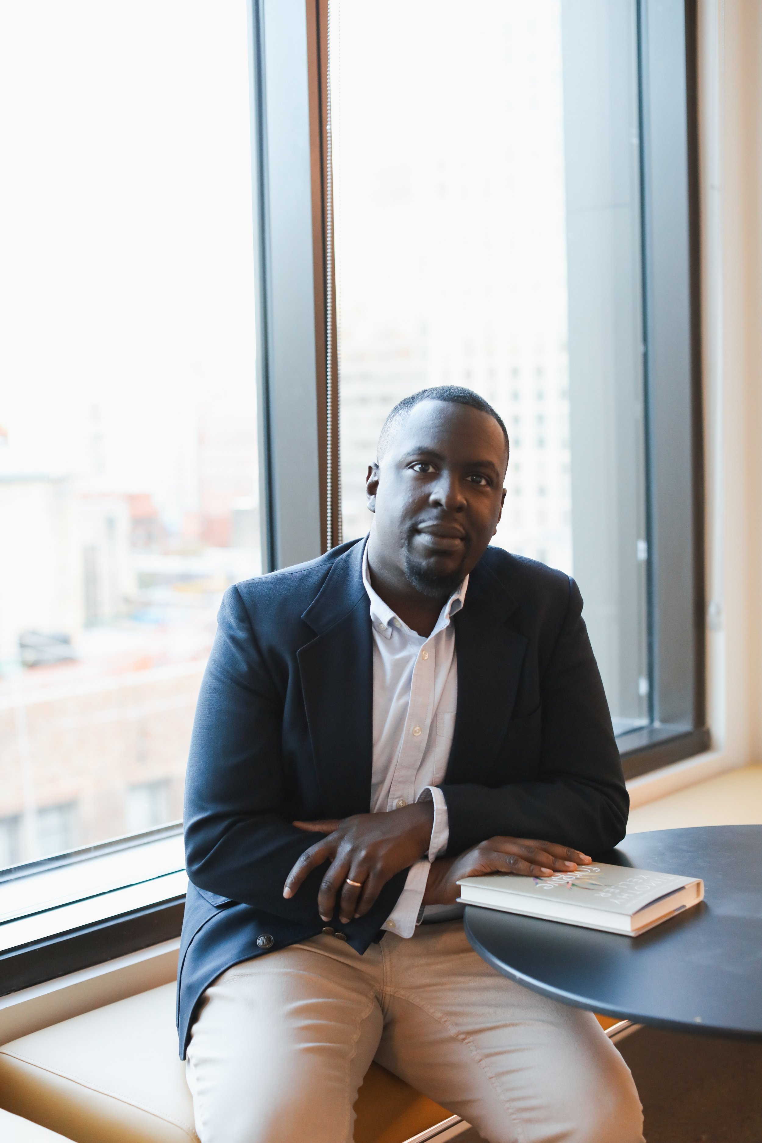 Ministry consultant and church leader Brandon Dunkley portrait sitting while holding a book at a table