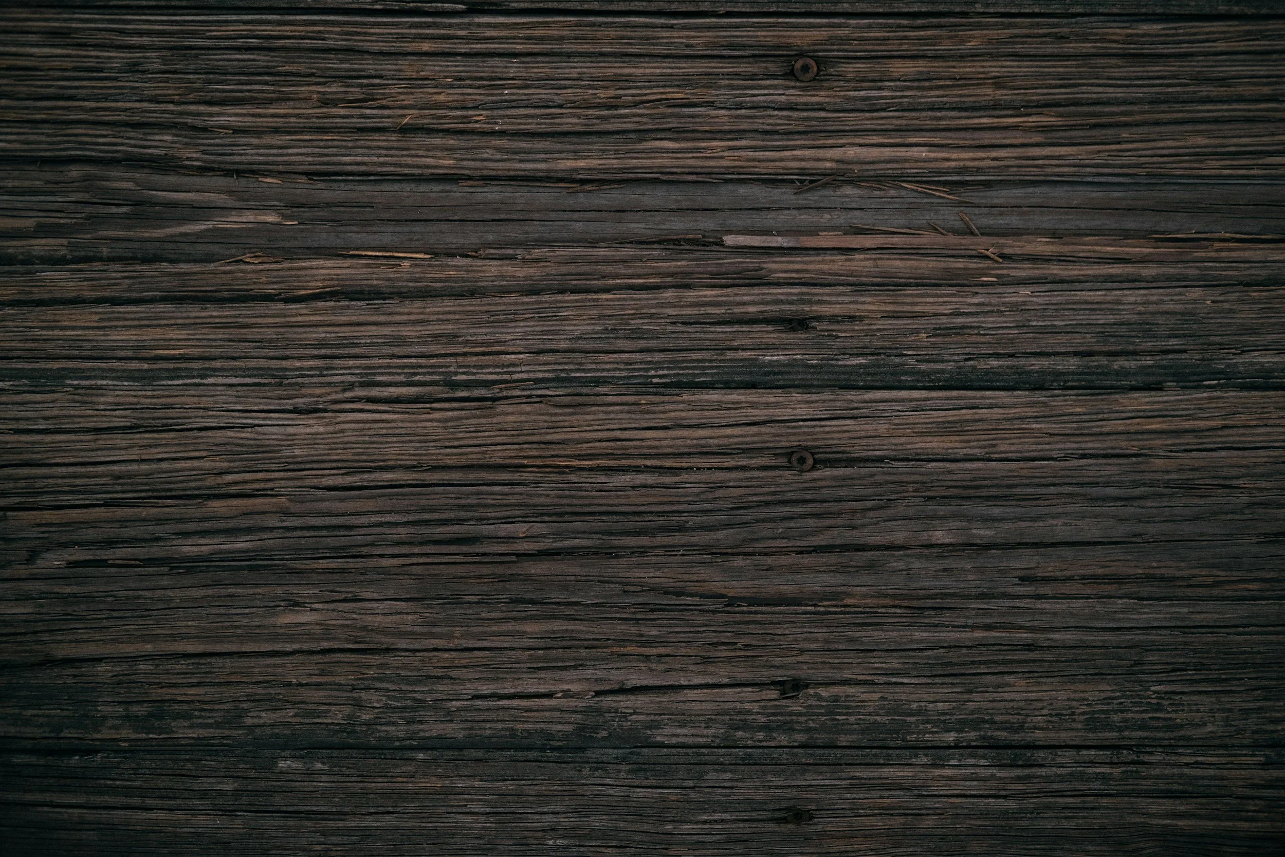 Close-up of weathered dark brown wooden planks with visible grain and knots.
