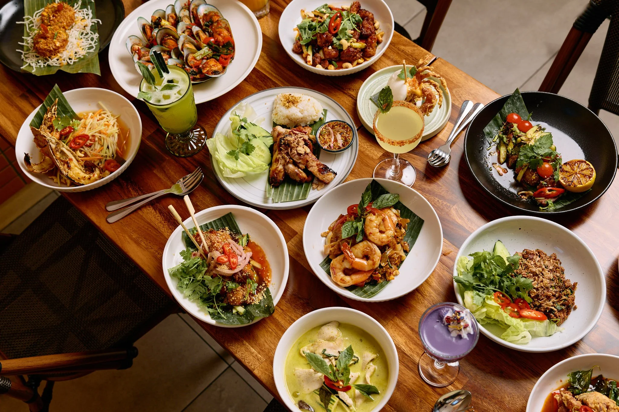 photo of a table full of vibrant thai dishes and drinks