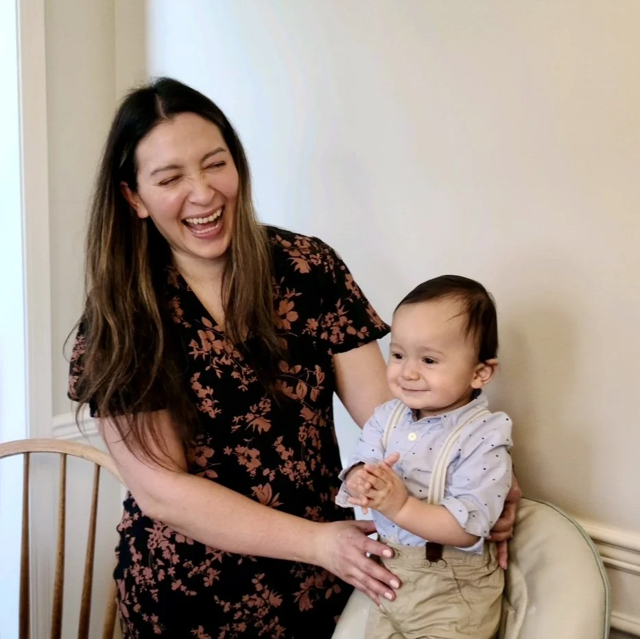 A woman and a young boy smiling and laughing together in an indoor setting.