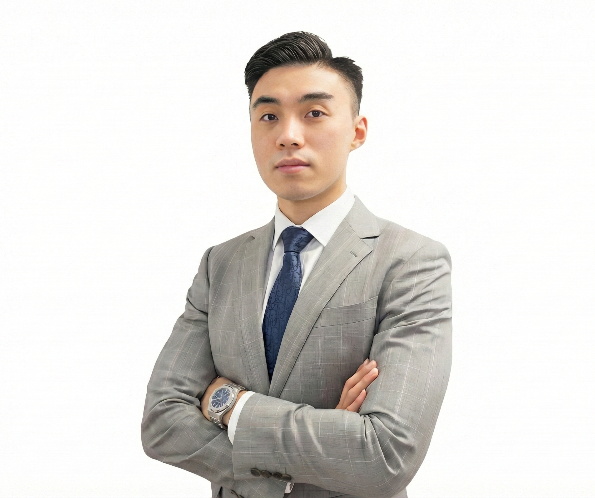 A man in a gray suit with arms crossed, wearing a blue tie and watch, standing against a white background.