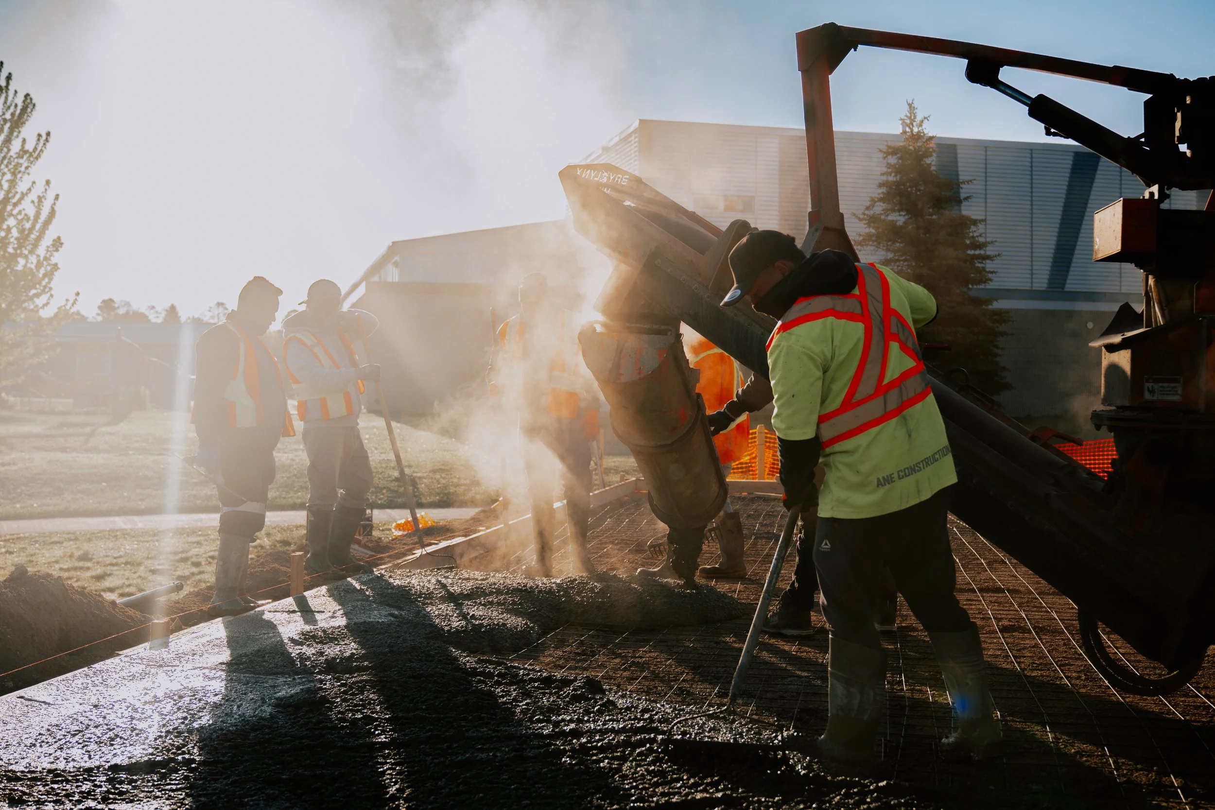 Construction workers pouring concrete on a building site during sunset