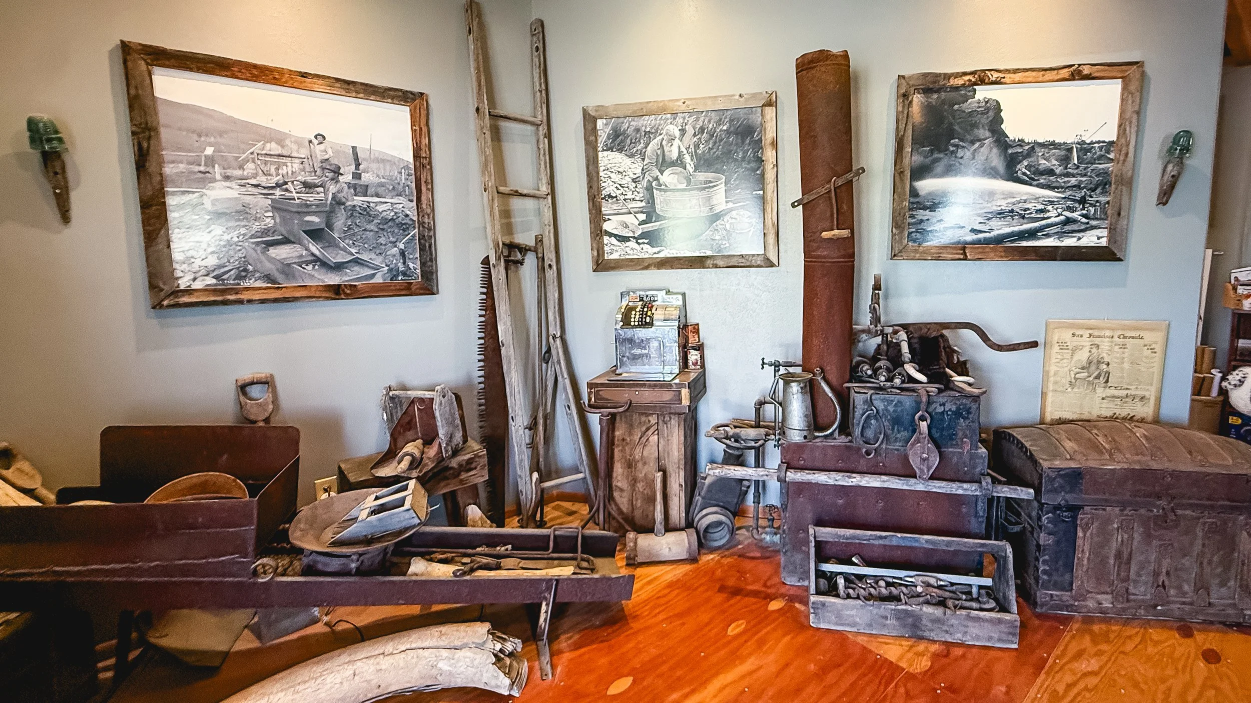 Wall display of vintage tools and equipment, including saws, a fire truck, a chest, and framed black-and-white photos of early industrial scenes.