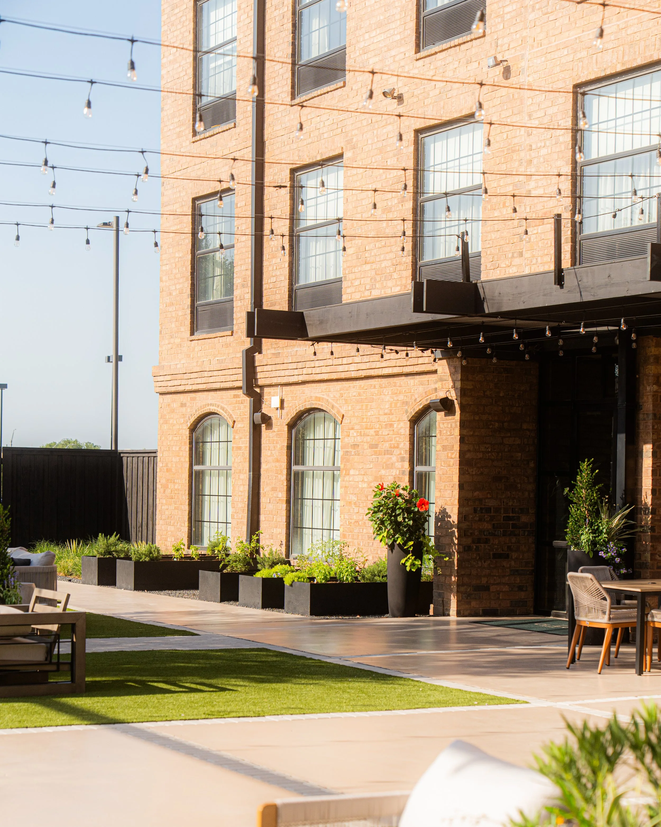 Outdoor patio with the herb garden and string lights at The Clara Hotel in Plano, Texas.