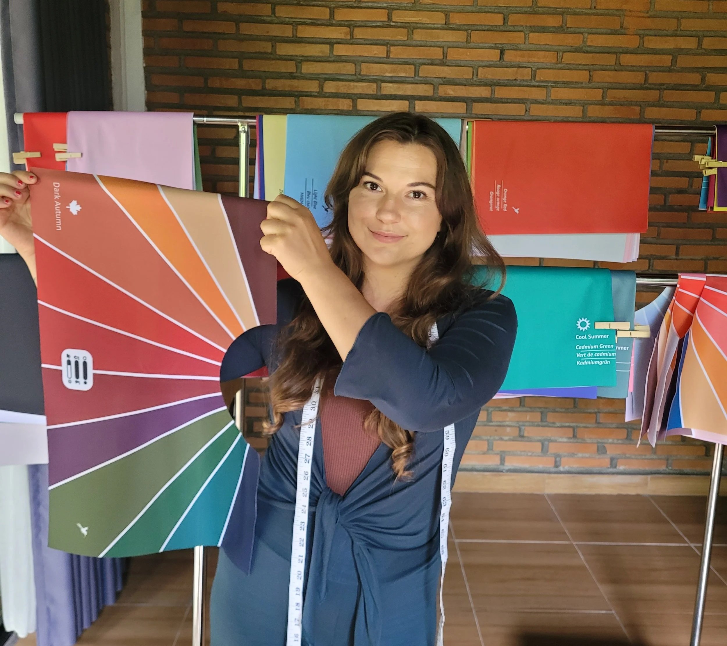 Woman holding a fabric sample from a color swatch display, with color swatches hanging in the background.