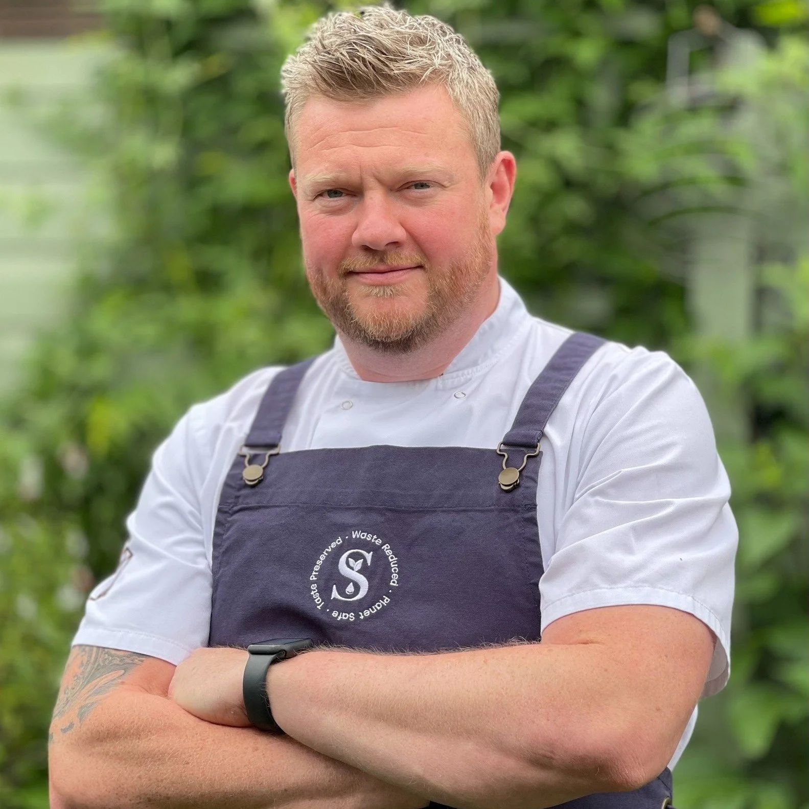 Matt Henman wearing chef whites and a blue Sustainable Sauces apron