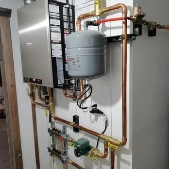 A boiler system with pipes, valves, and a pressure tank installed on a wall.