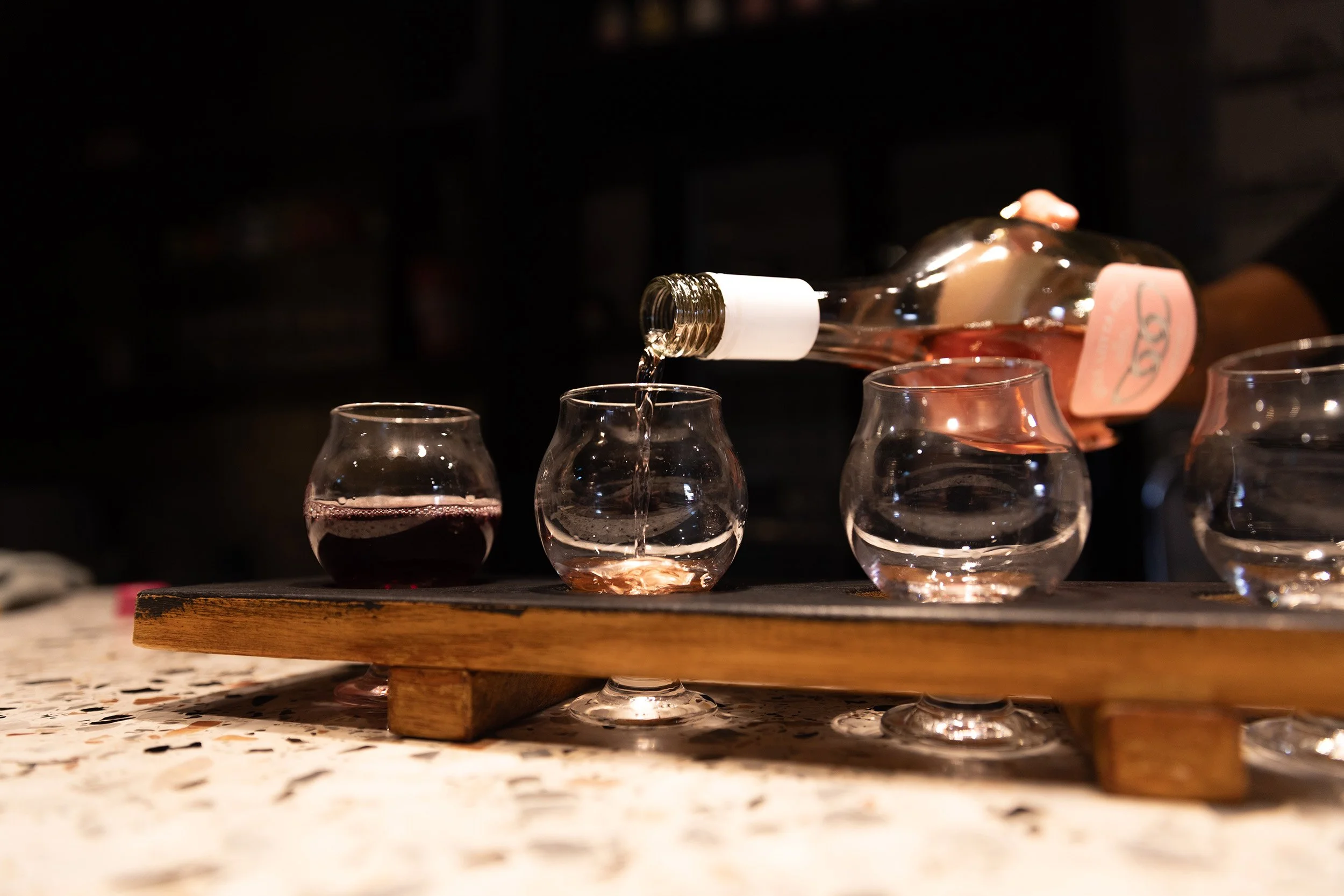 Pouring a tasting paddle of Forage Supply Co wine at Old Mill Brewery in Tanunda, Barossa Valley, featuring rosé and red wine served in stemless tasting glasses on a rustic wooden paddle inside the historic brewery venue.