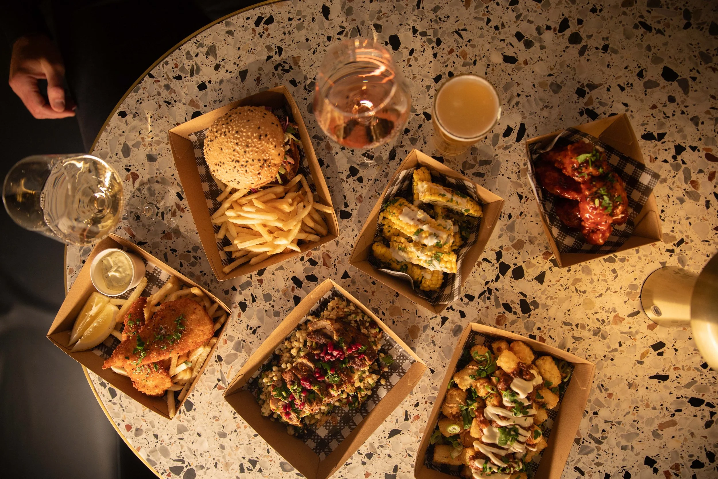 Overhead view of food and drinks at Old Mill Brewery featuring burgers, fried chicken, loaded fries and share plates paired with craft beer and Barossa Valley wine inside the historic brewery and dining venue in the Barossa.