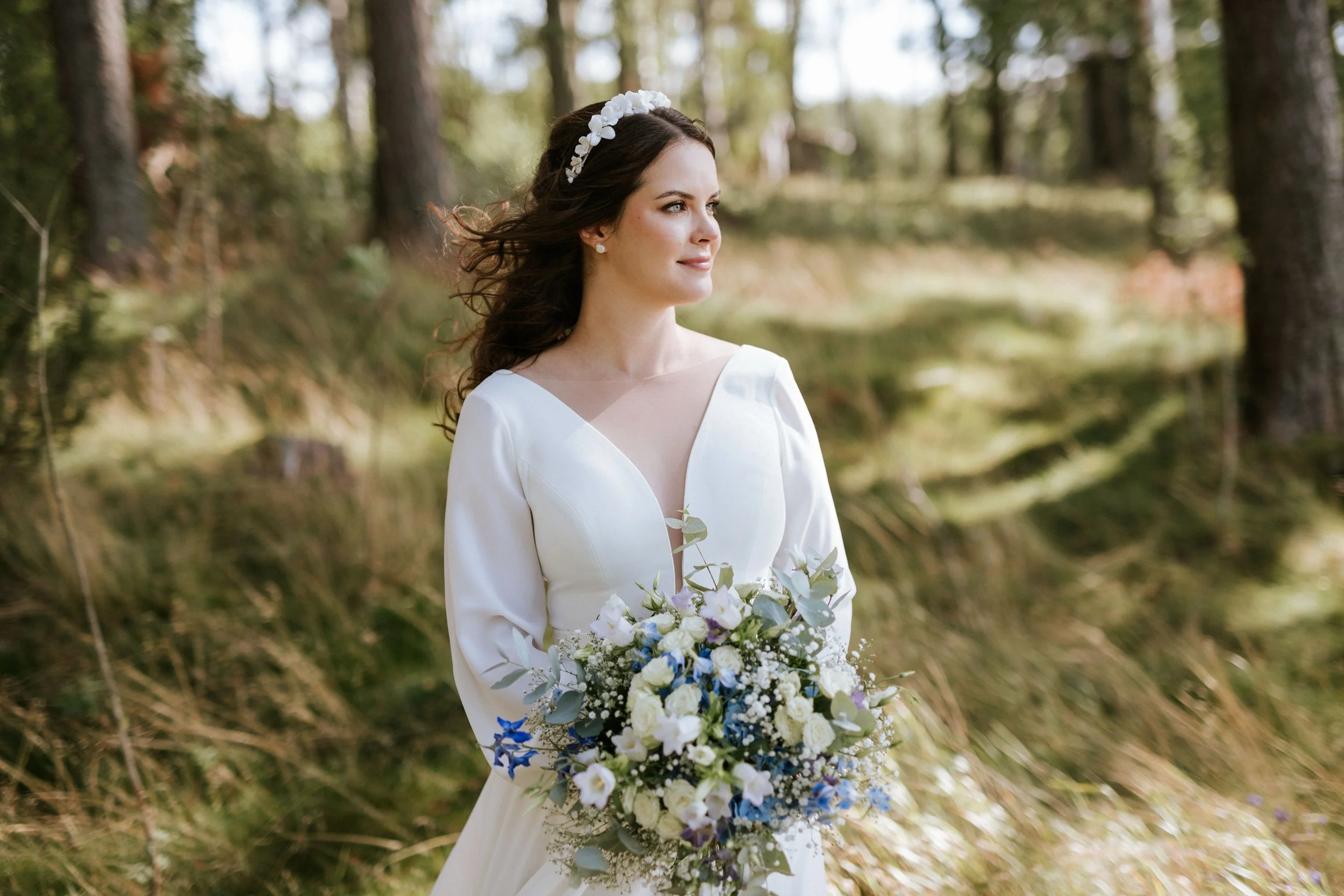 Häämeikki ja kampaus morsiamella kuvattuna luonnossa, pienessä tuulessa