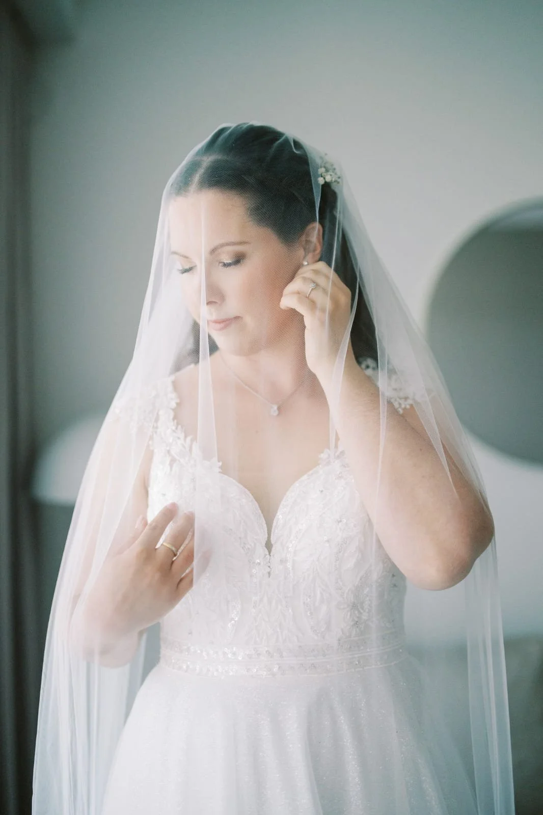 Häämeikki ja kampaus kuvattuna morsiamella hääpäivänä hunnun läpi rauhallisessa tunnelmassa