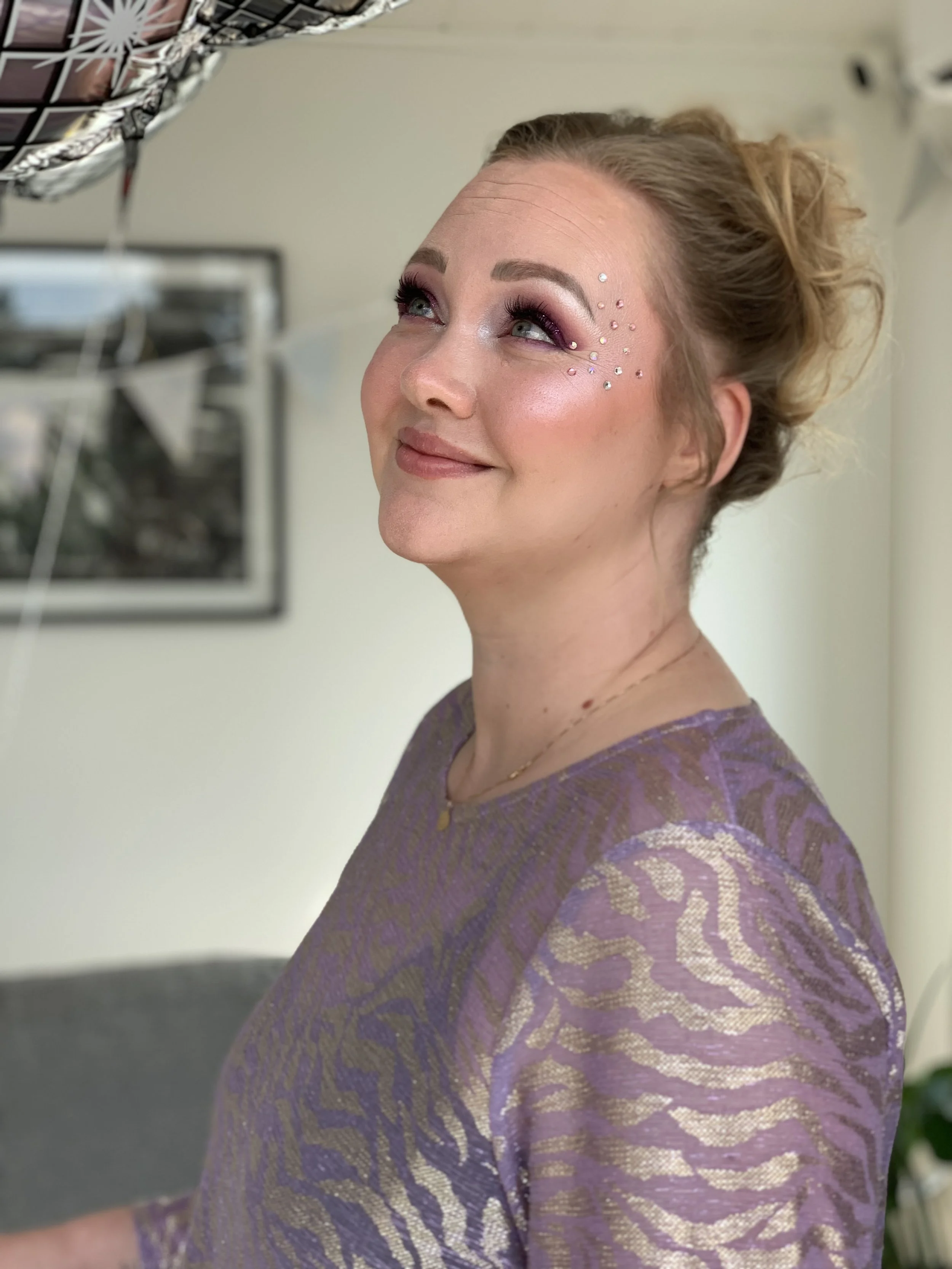 Juhlameikki ja kampaus kuvattuna vaaleahiuksisella, hymyilevällä naisella