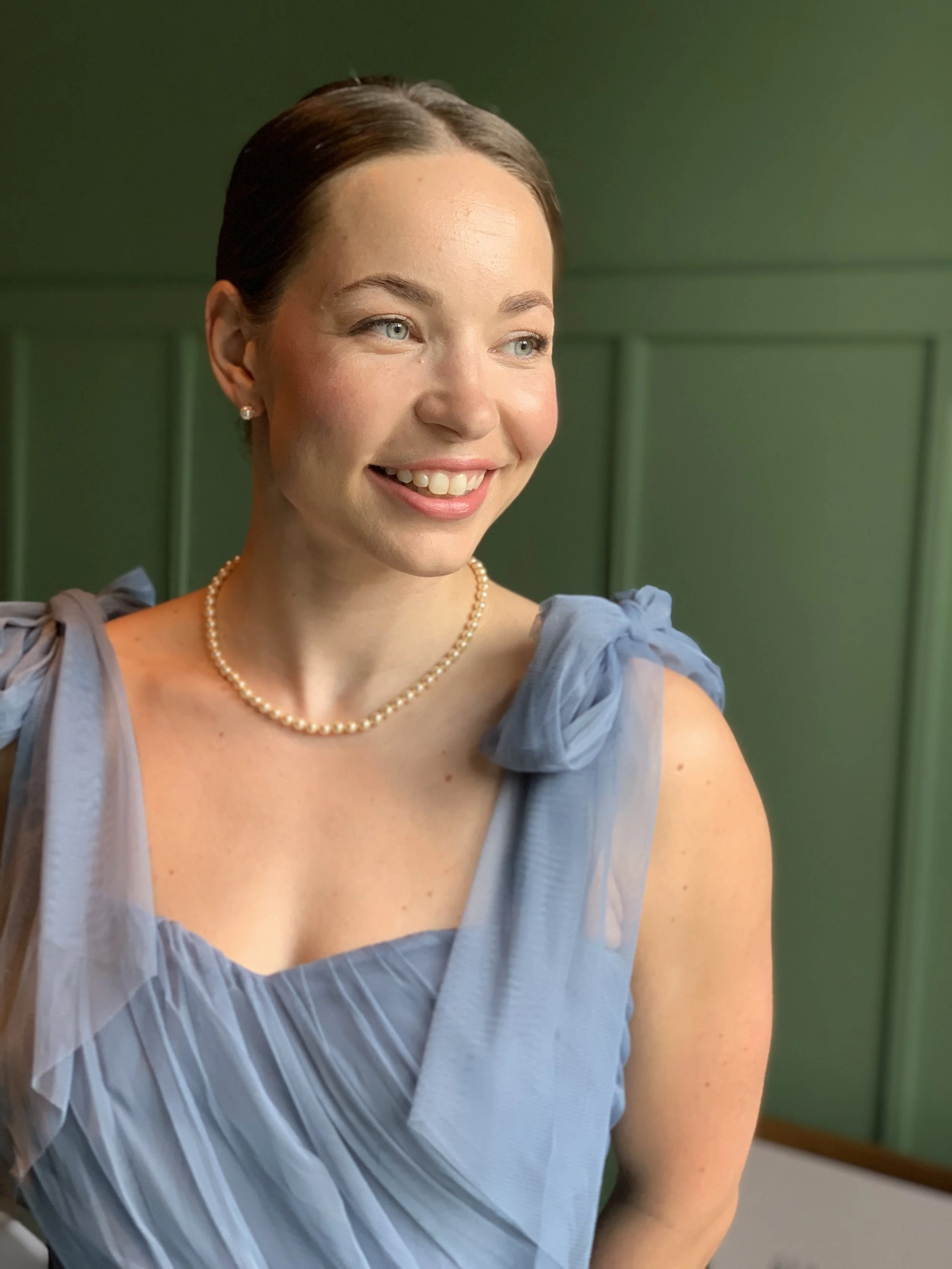 Tyylikäs, luonnollinen juhlameikki hymyilevällä sinimekkoisella naisella