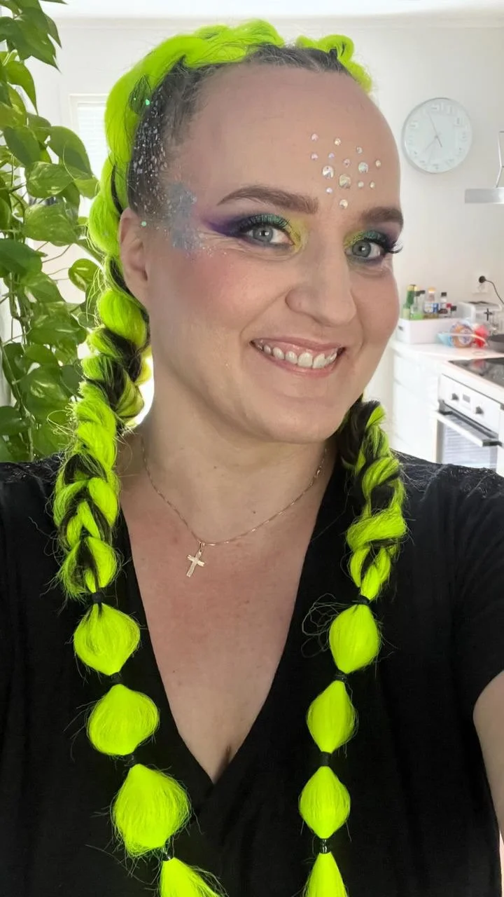 Vihreät kuituletit ja festarimeikki hymyilevällä naisella