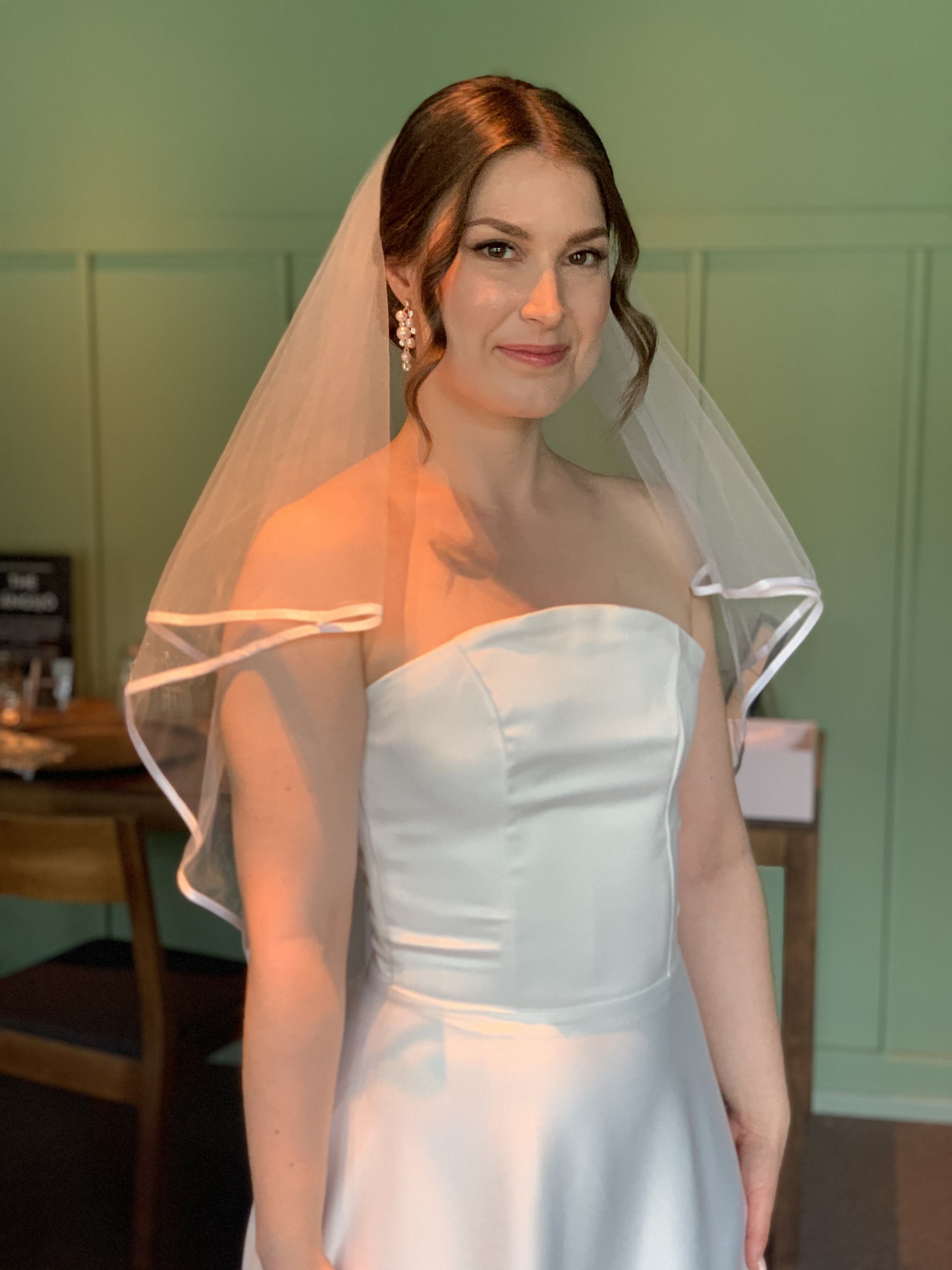 Häämeikki ja hääkampaus hunnulla tummatukkaisella morsiamella