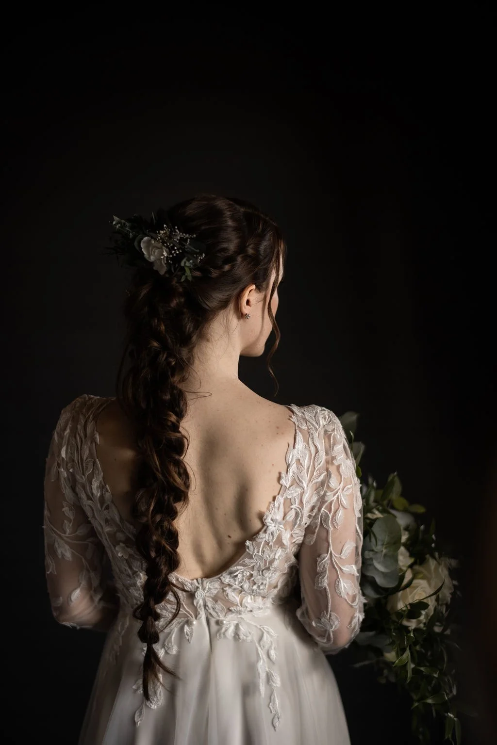 Upea morsiamen lettikampaus kuvattuna takaapäin tumman sävyisessä kuvassa.