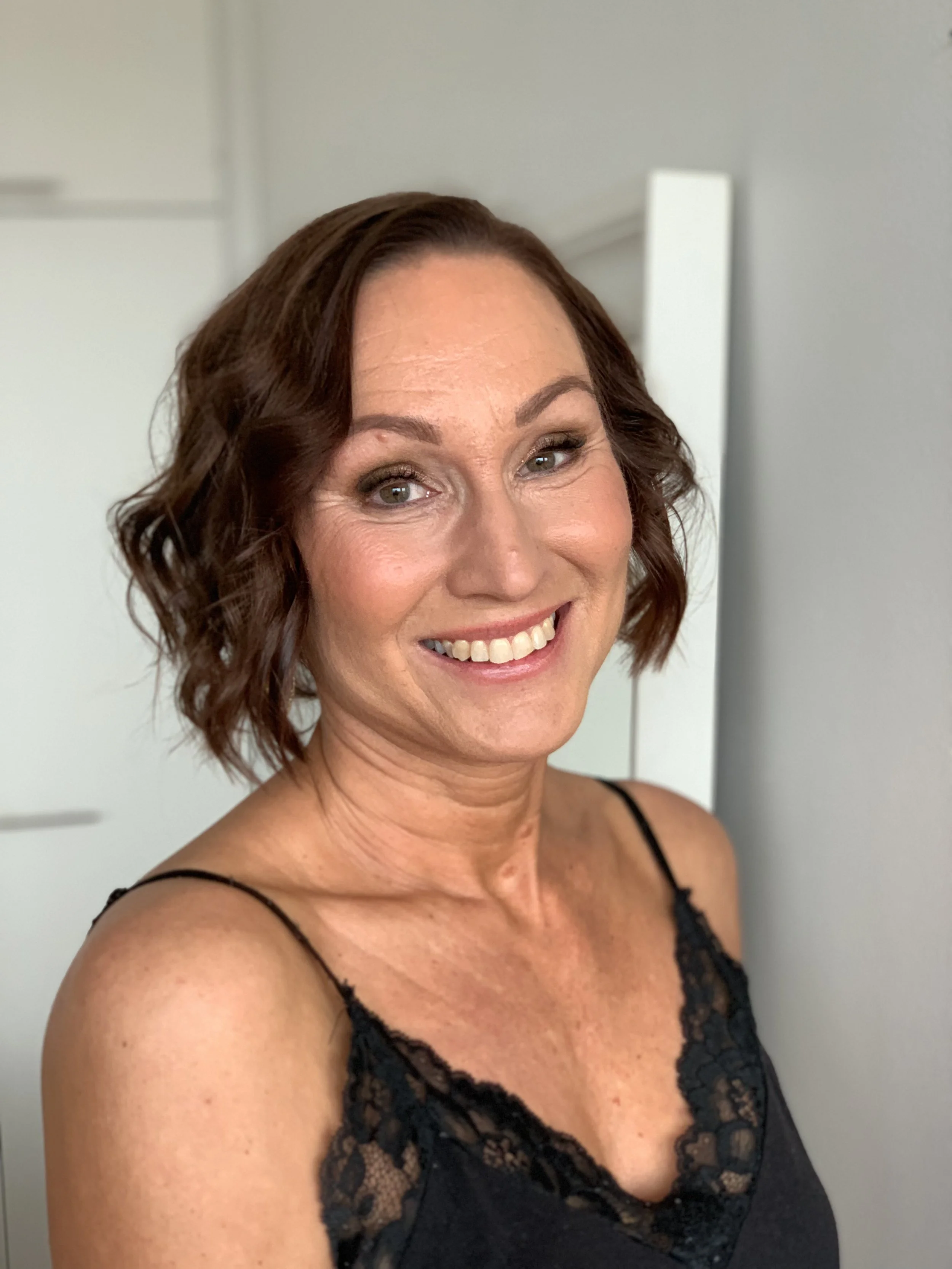 Juhlakampaus ja juhlameikki kuvattuna tummahiuksisella, hymyilevällä naisella