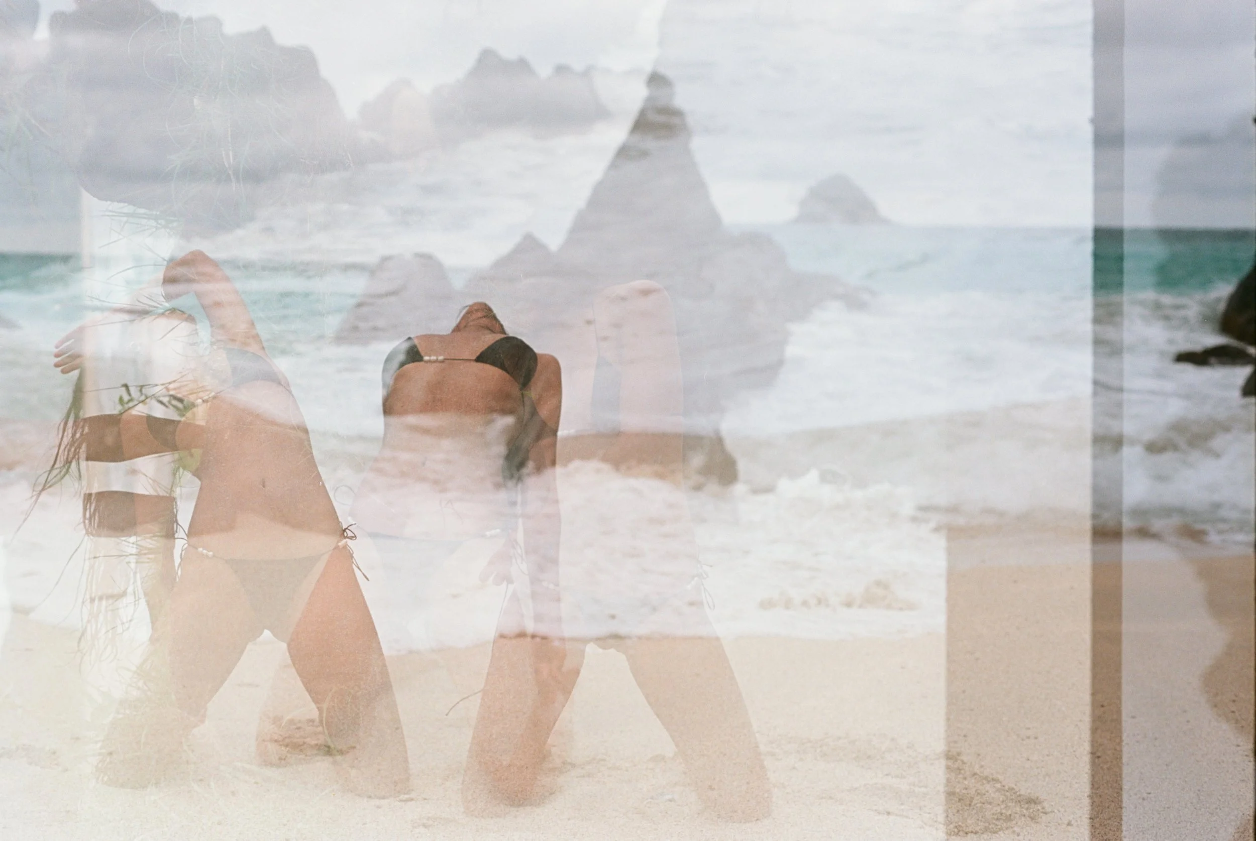 A layered image showing a woman in a black bikini on the beach, with rocks in the ocean and a cloudy sky in the background.
