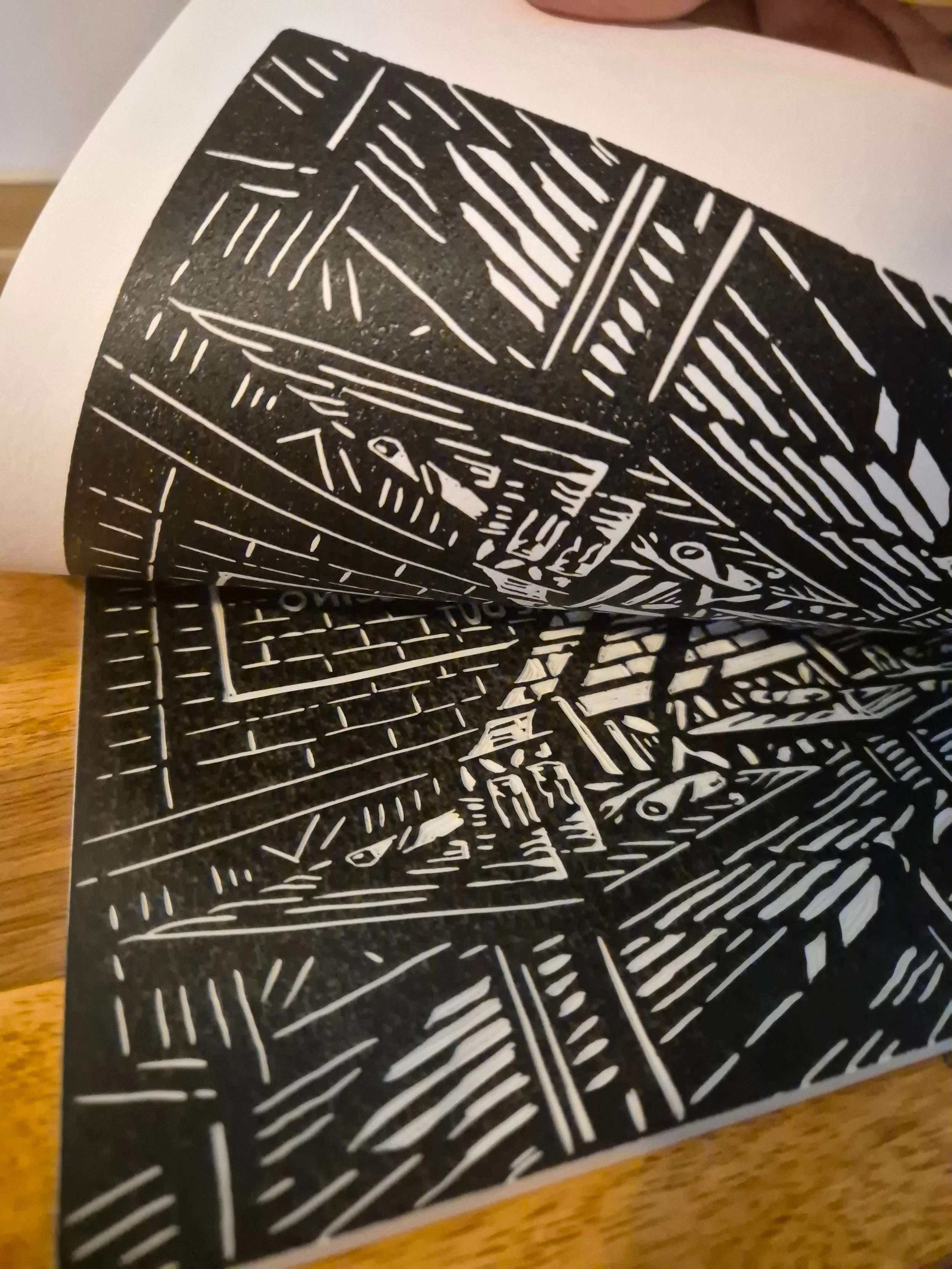 Linogravure « Caffè all’Angolo » partiellement roulée, mettant en valeur la souplesse du papier d’art et les lignes gravées de la façade de pizzeria en noir et blanc