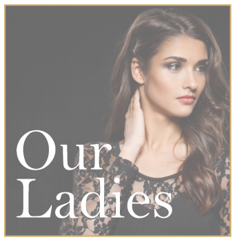 A woman with long, wavy brunette hair wearing a black lace top, looking to the side with a serious expression, with the words 'Our Ladies' in white text.