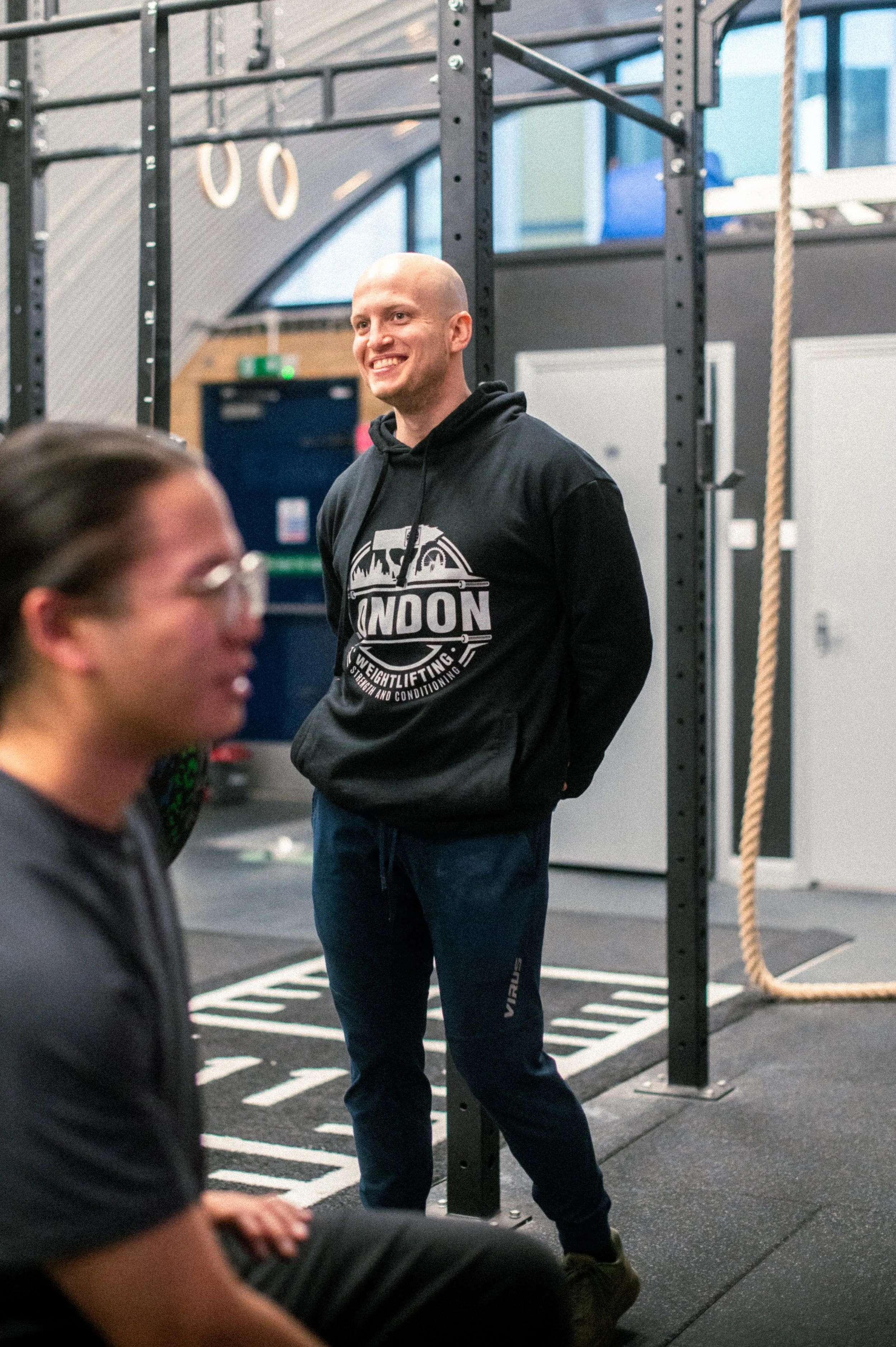 People lifting weights inside a gym with a sign that reads 'London Weightlifting' above the entrance.