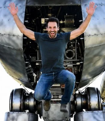 Overjoyed man, arms aloft, jumping out of a large robot.