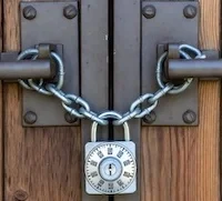 Heavy padlock securing two sturdy wooden doors.