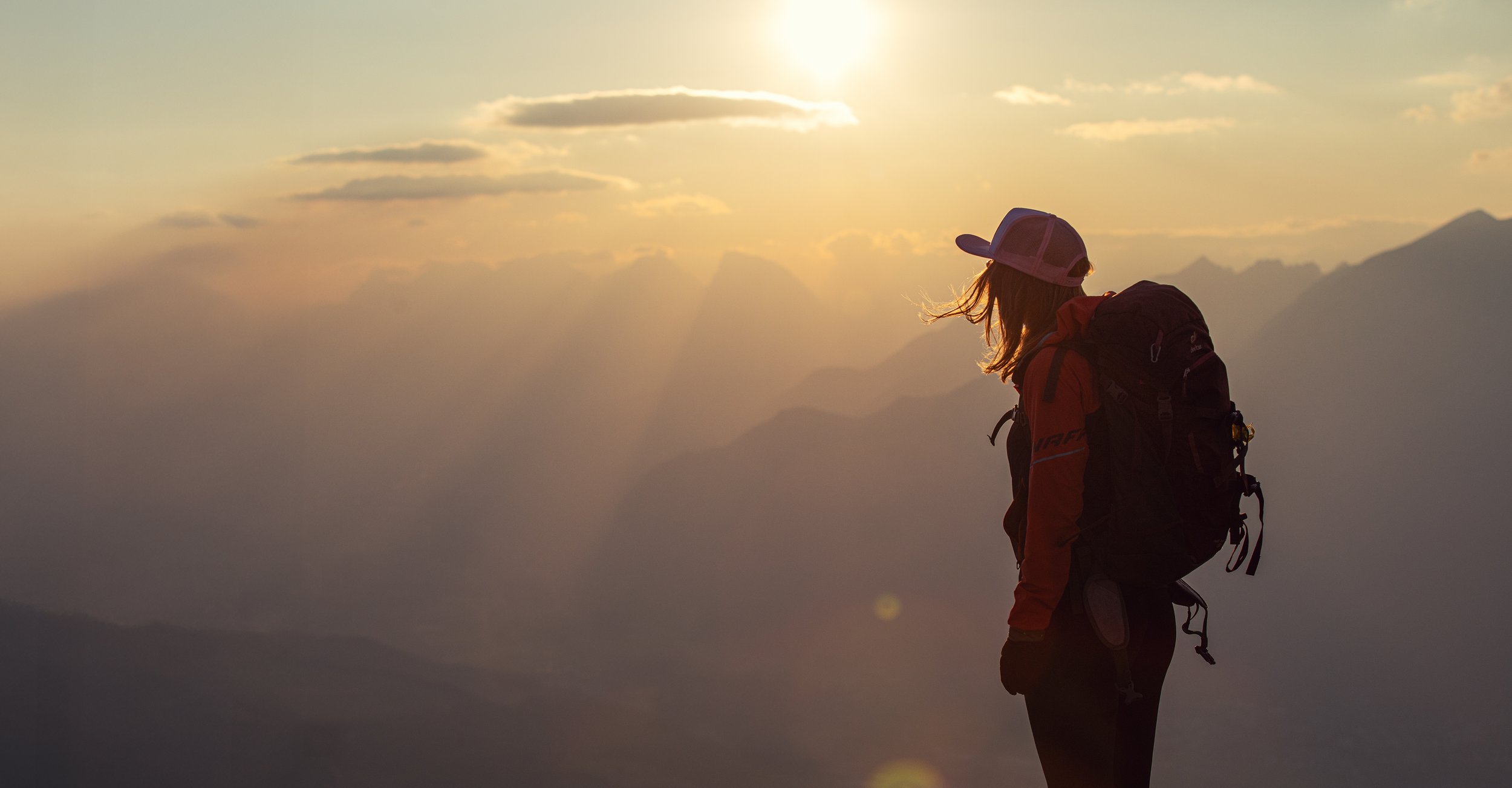 Frau mit Rucksack im Profil bei Sonnenuntergang in den österreichischen Bergen. Chris Reichl Outdoor.