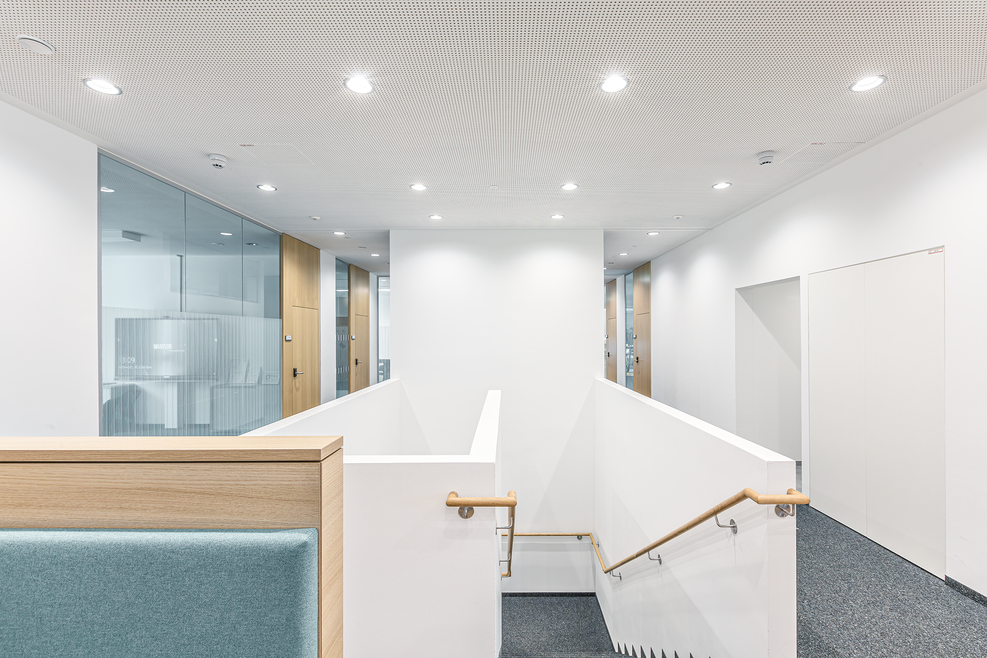 Inneneingang mit Treppe und Glaswänden in einem modernen Bürogebäude. Chris Reichl Architektur.