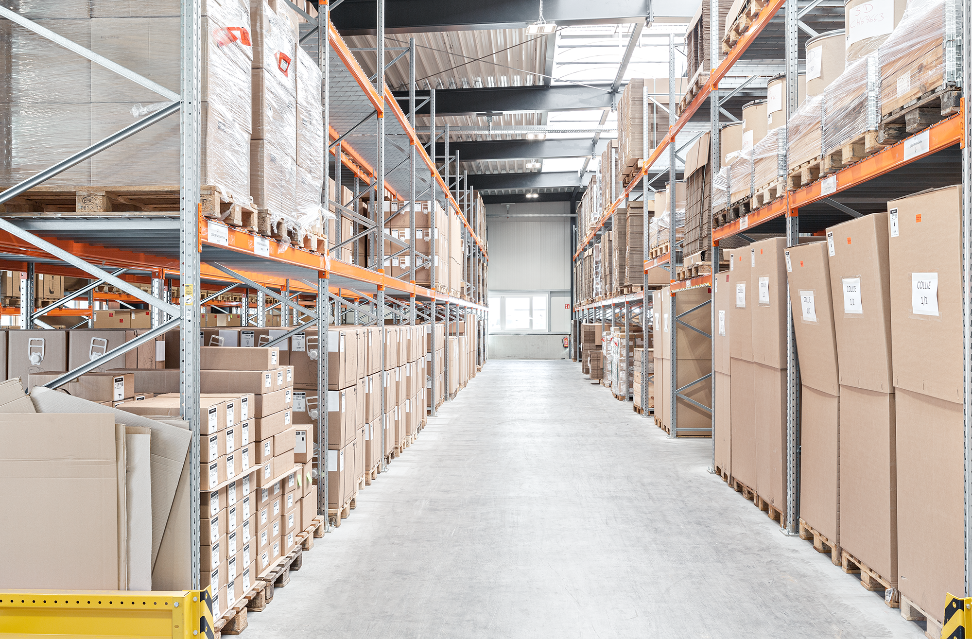 Lagerraum mit Regalen voller Kartons und Verpackungsmaterial in einem großen Lagergebäude. Chris Reichl On location.