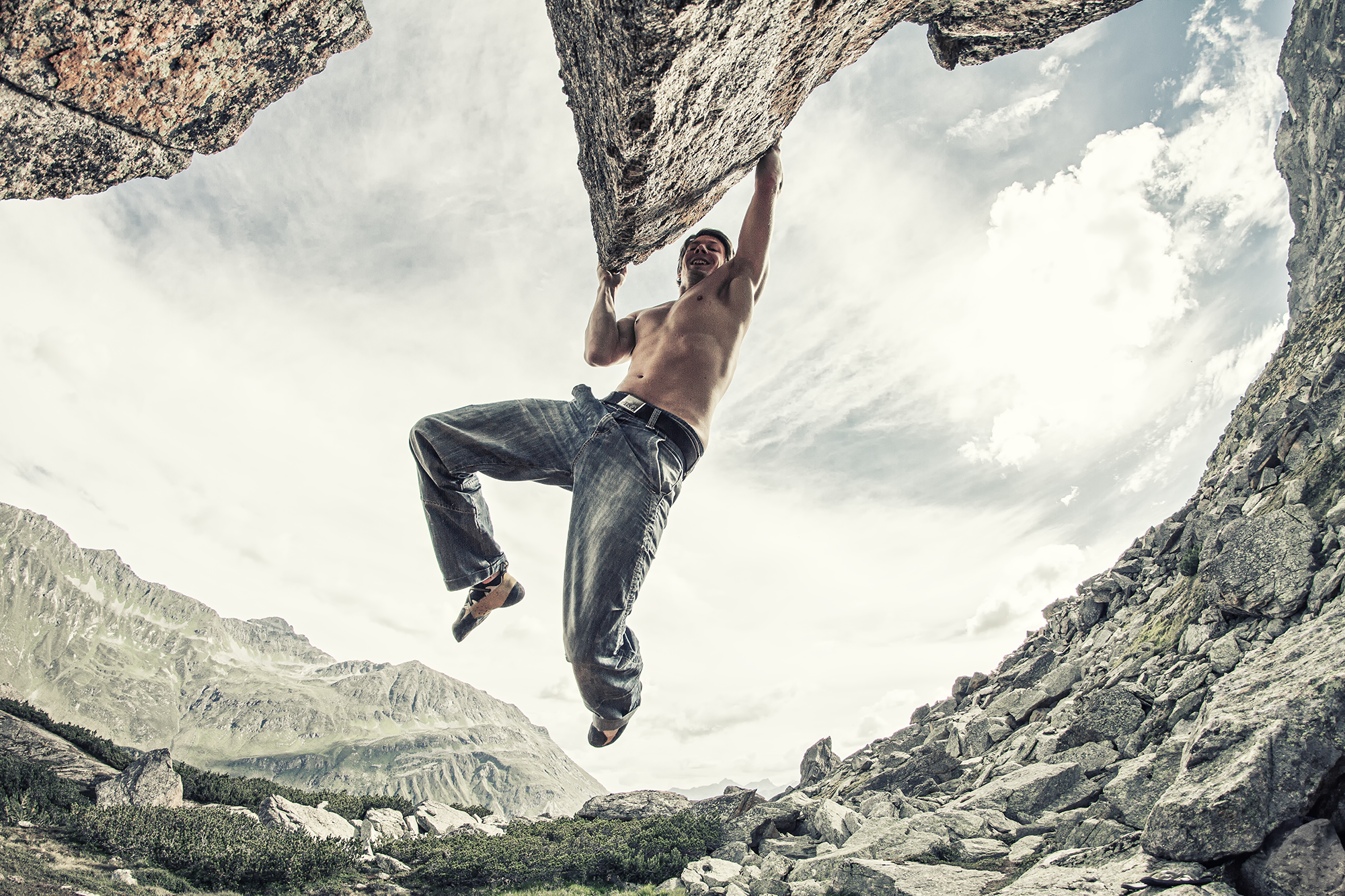 Ein nackter Mann klettert an einer Felswand in einer felsigen Berglandschaft