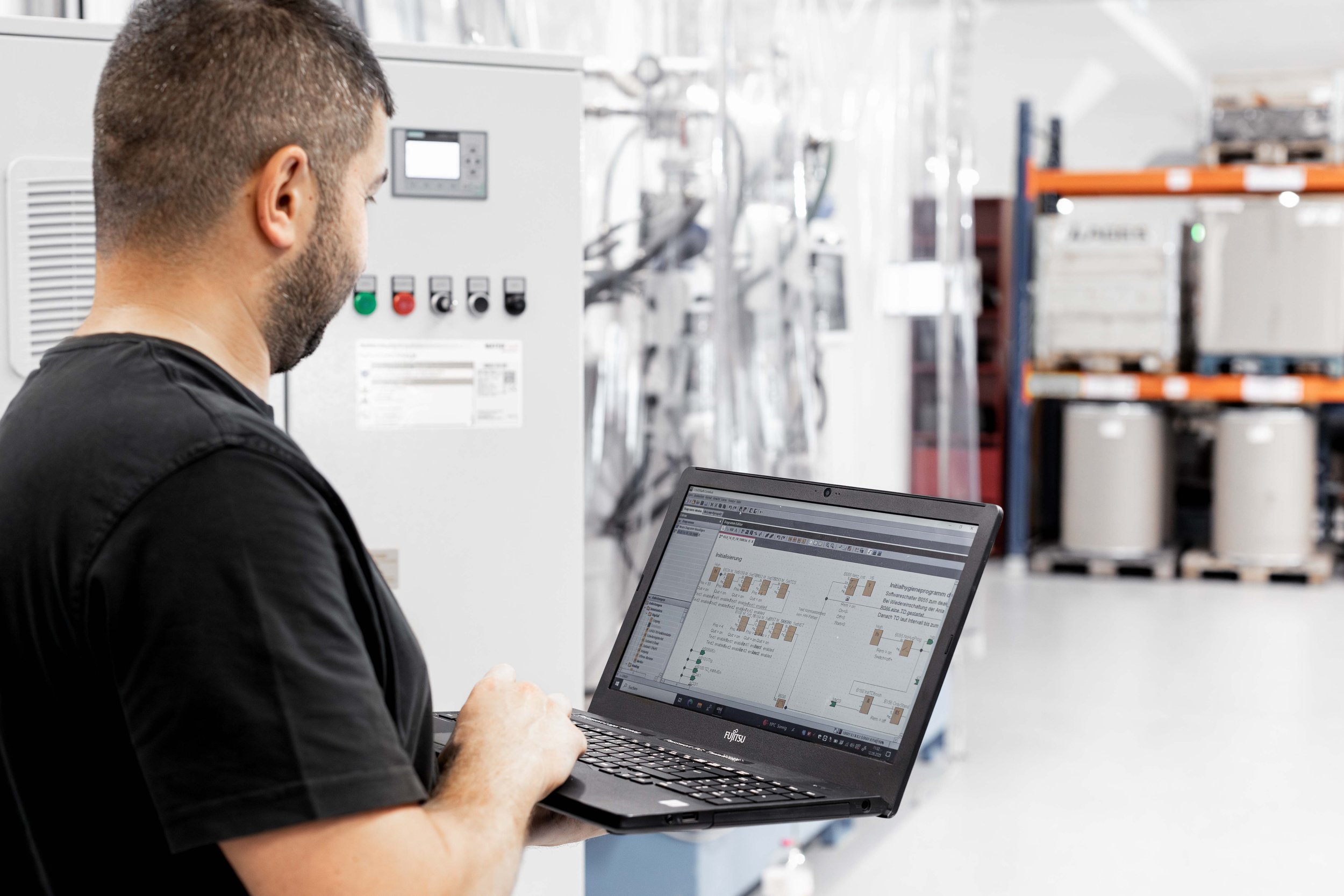 Mann arbeitet mit Laptop in einer Industriehalle