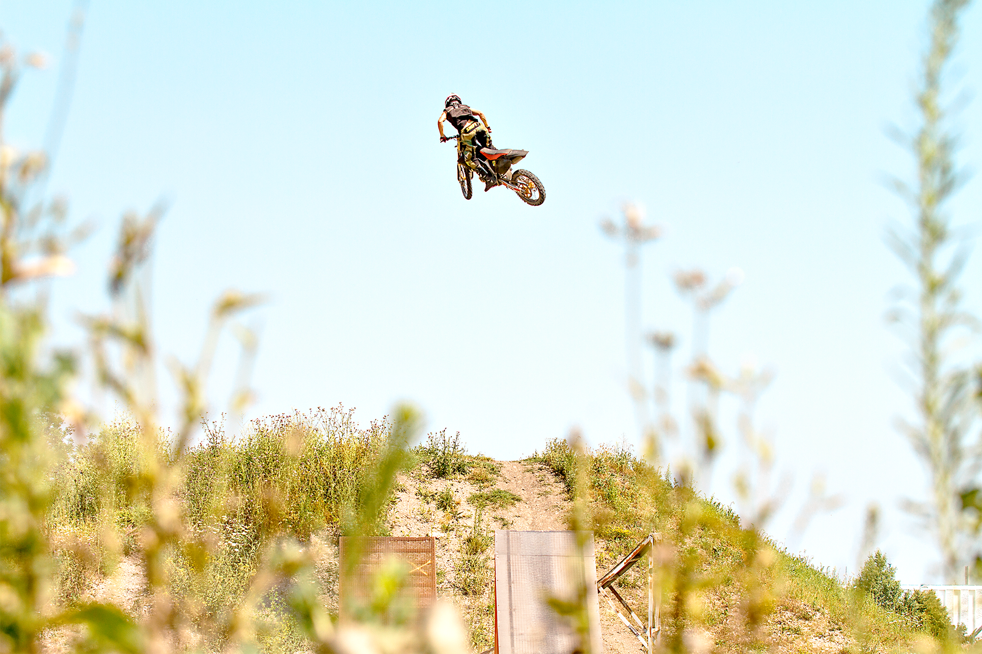 Ein Motocross-Fahrzeug fliegt durch die Luft bei einem Sprung auf einem dirt-track im Freien bei sonnigem Wetter.