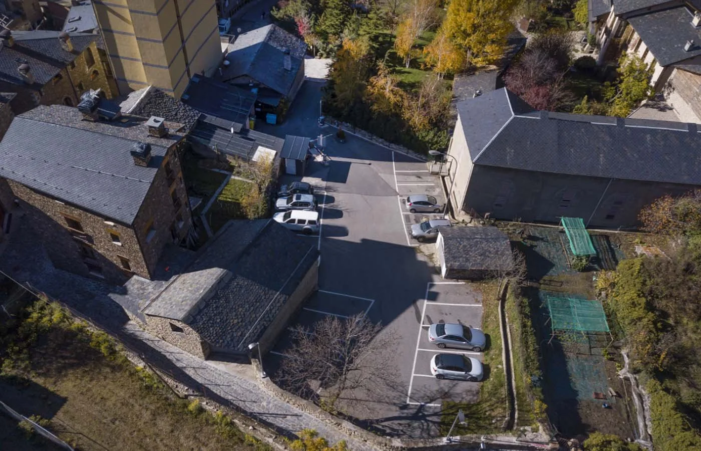 Vista aérea de un estacionamiento rodeado de edificios y árboles con hojas de colores otoñales.