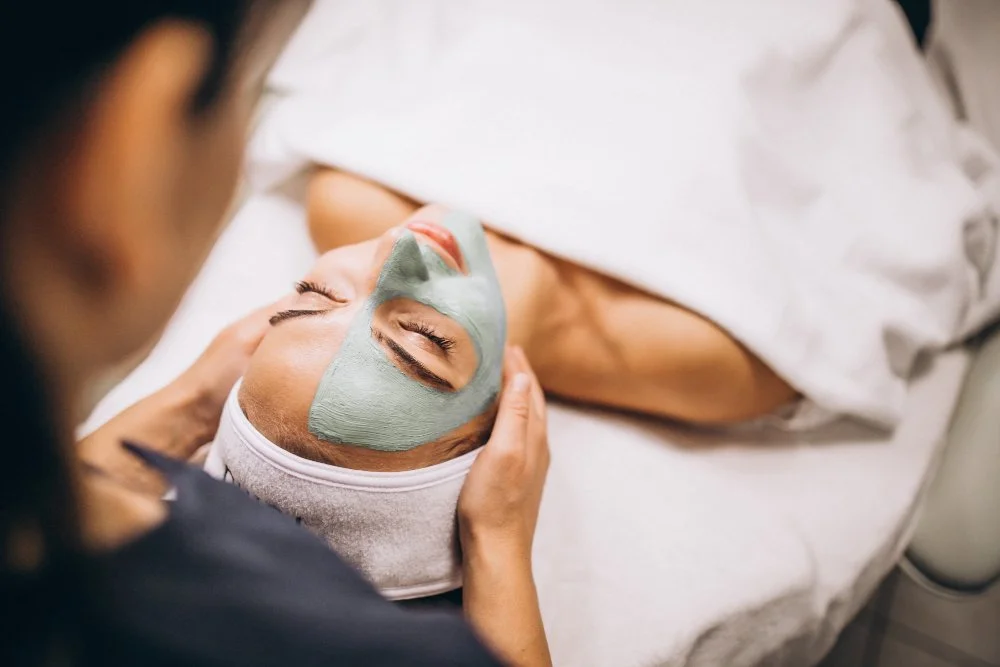 Nahaufnahme einer Frau, die ein Massage erhält, während sie auf einer Massagebank liegt, mit einem Handgriff, der den Nacken oder oberen Rücken massiert.