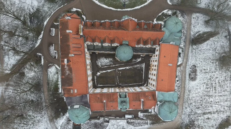 Vogelperspektive auf eine historische Gebäudeanlage mit roten Dächern, Innenhof und umliegender verschneiter Landschaft. Schloss Celle. Schloss. Celle. Luftaufnahme Celle 
