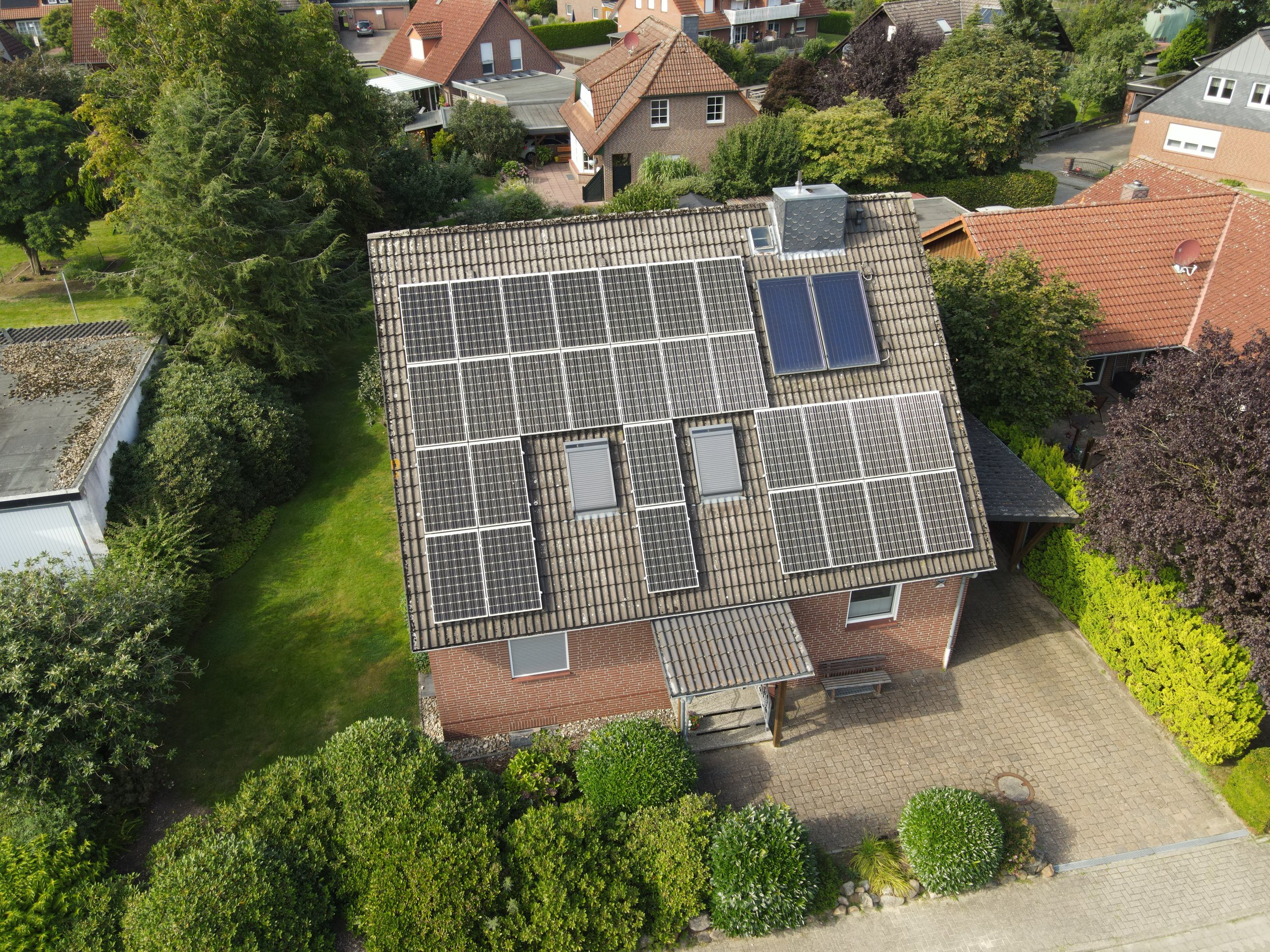 Vogelperspektive auf ein Haus mit Solaranlagen auf dem Dach, umgeben von Bäumen und anderen Häusern in einer Wohngegend. Solar und Photovoltaikanlage, Luftaufnahme, Drohnenaufnahme Celle, Bergen
