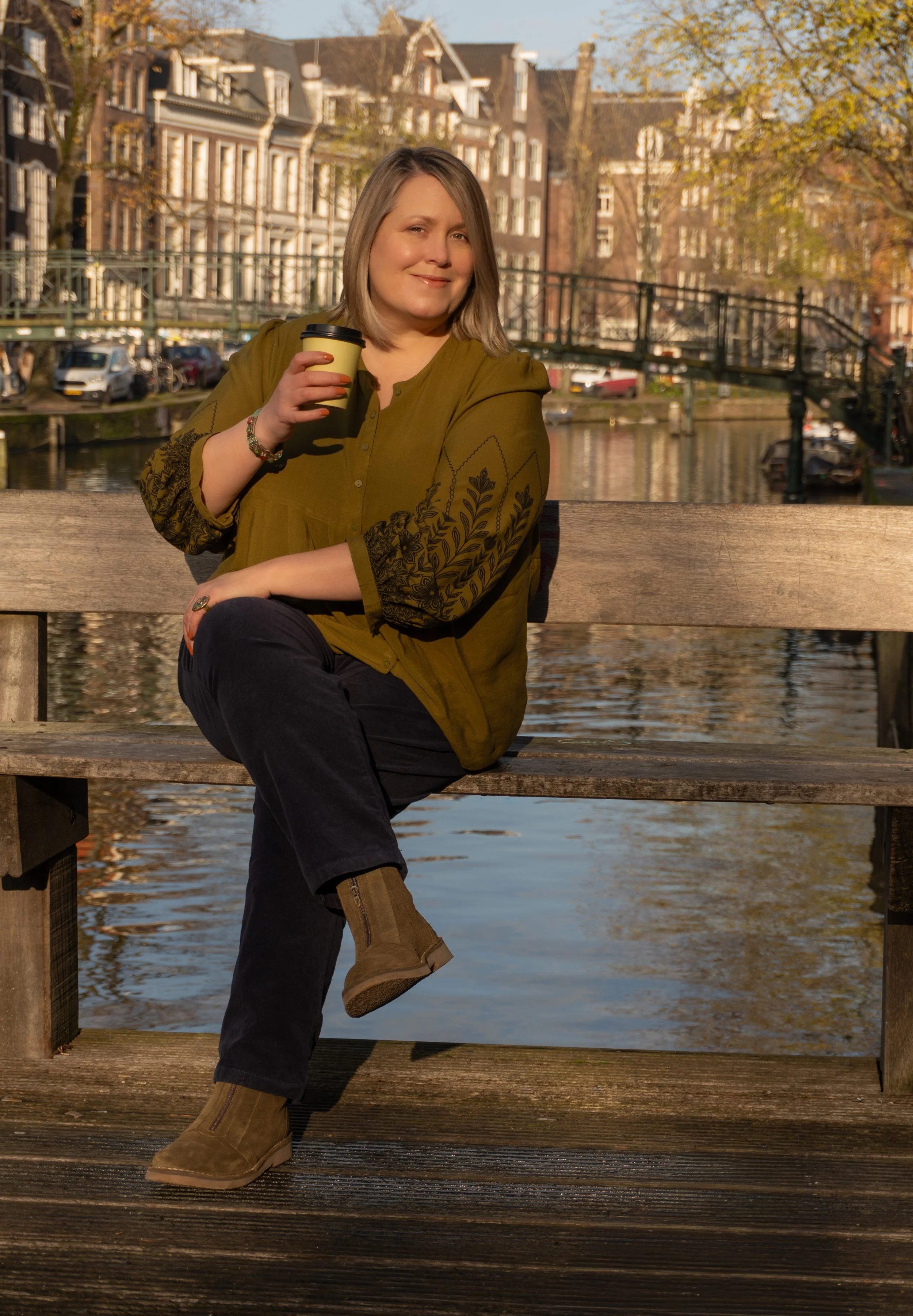 Beth sitting on a bench with canal in background