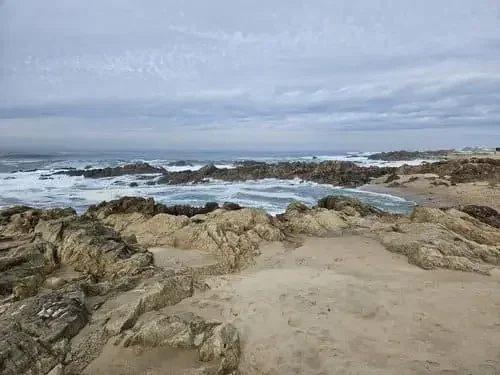 Plage de sable avec des rochers, océan avec des vagues et ciel nuageux, Piscina das Marés, Alvaro Siza