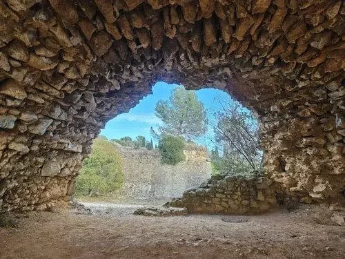 photo d'une grotte de pierres qui donne la vue en tunnel sur un paysage naturel