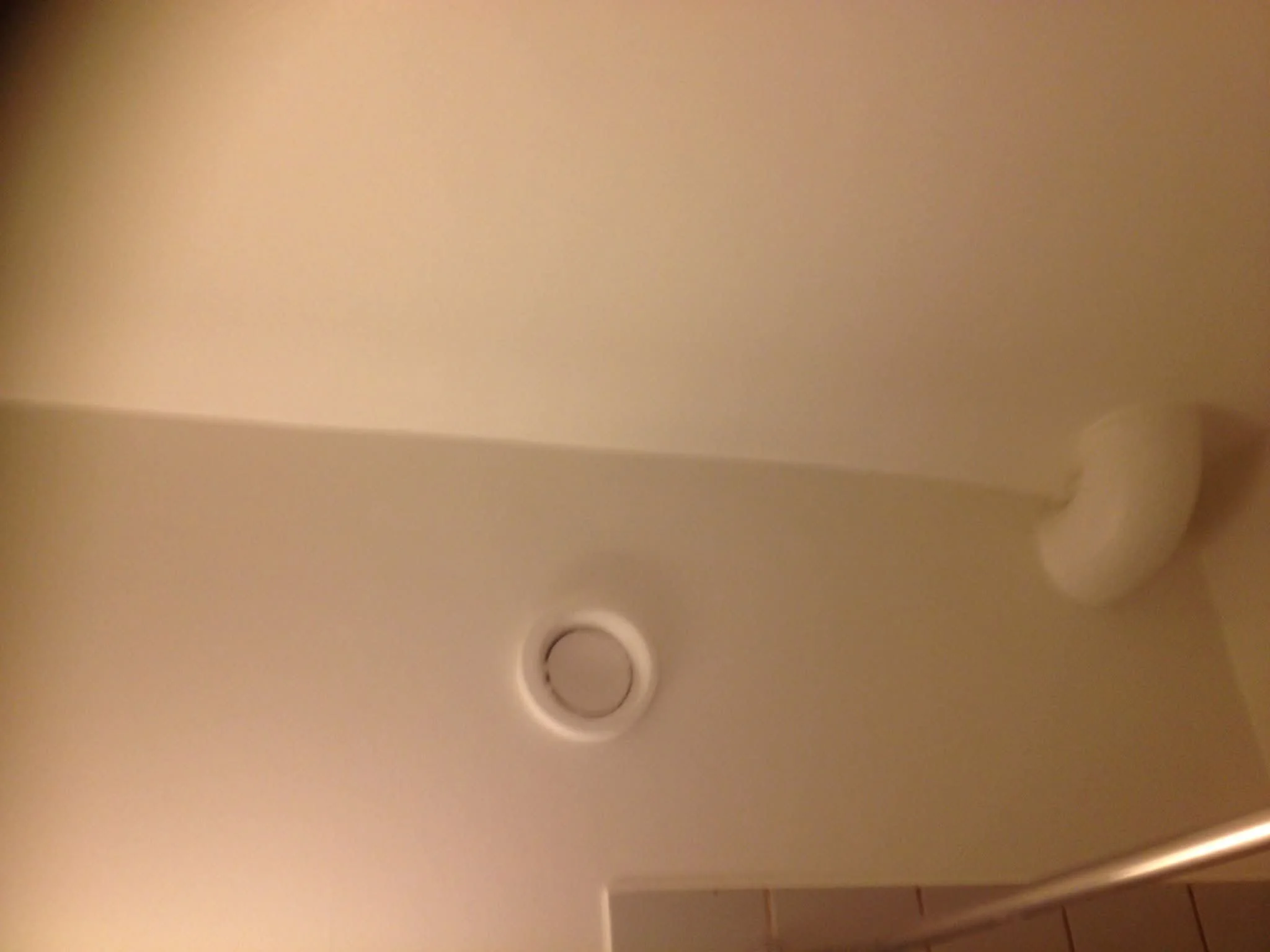 Plafond de salle avec un détecteur de fumée et un éclairage encastré.