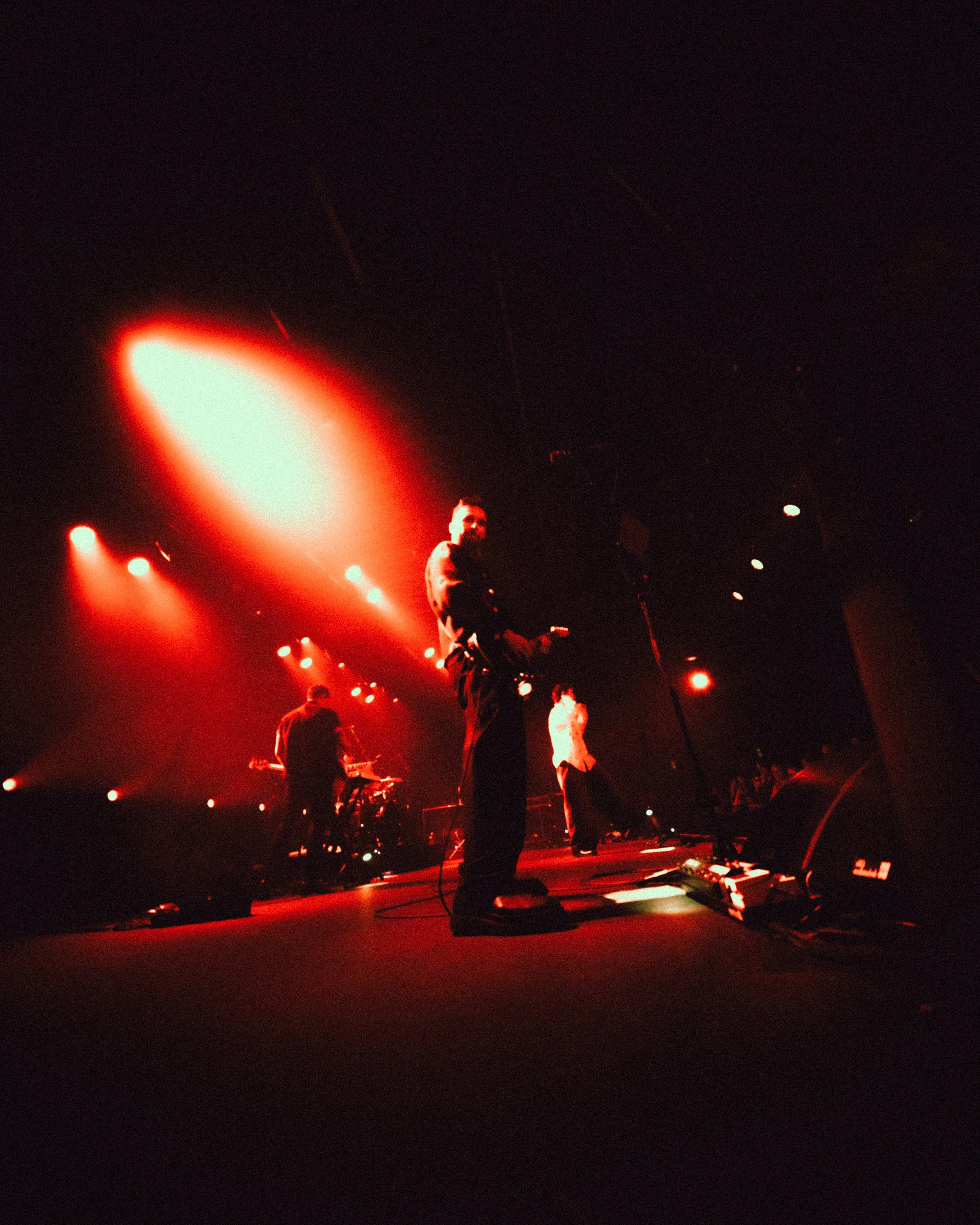 Band performing on stage with red lighting