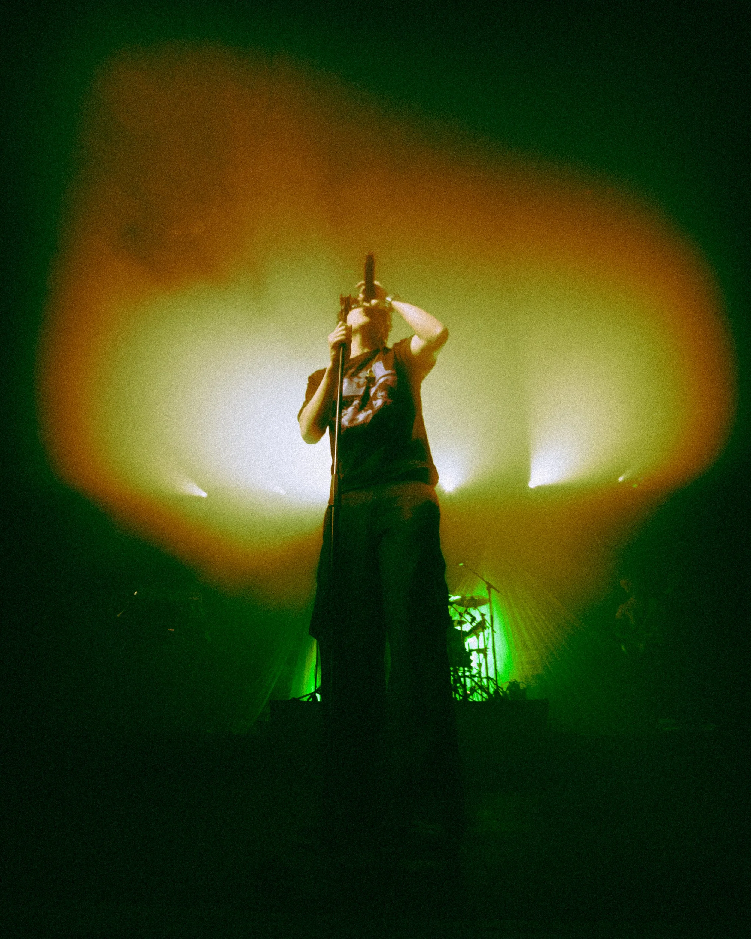 A singer performing on stage with colorful lighting.